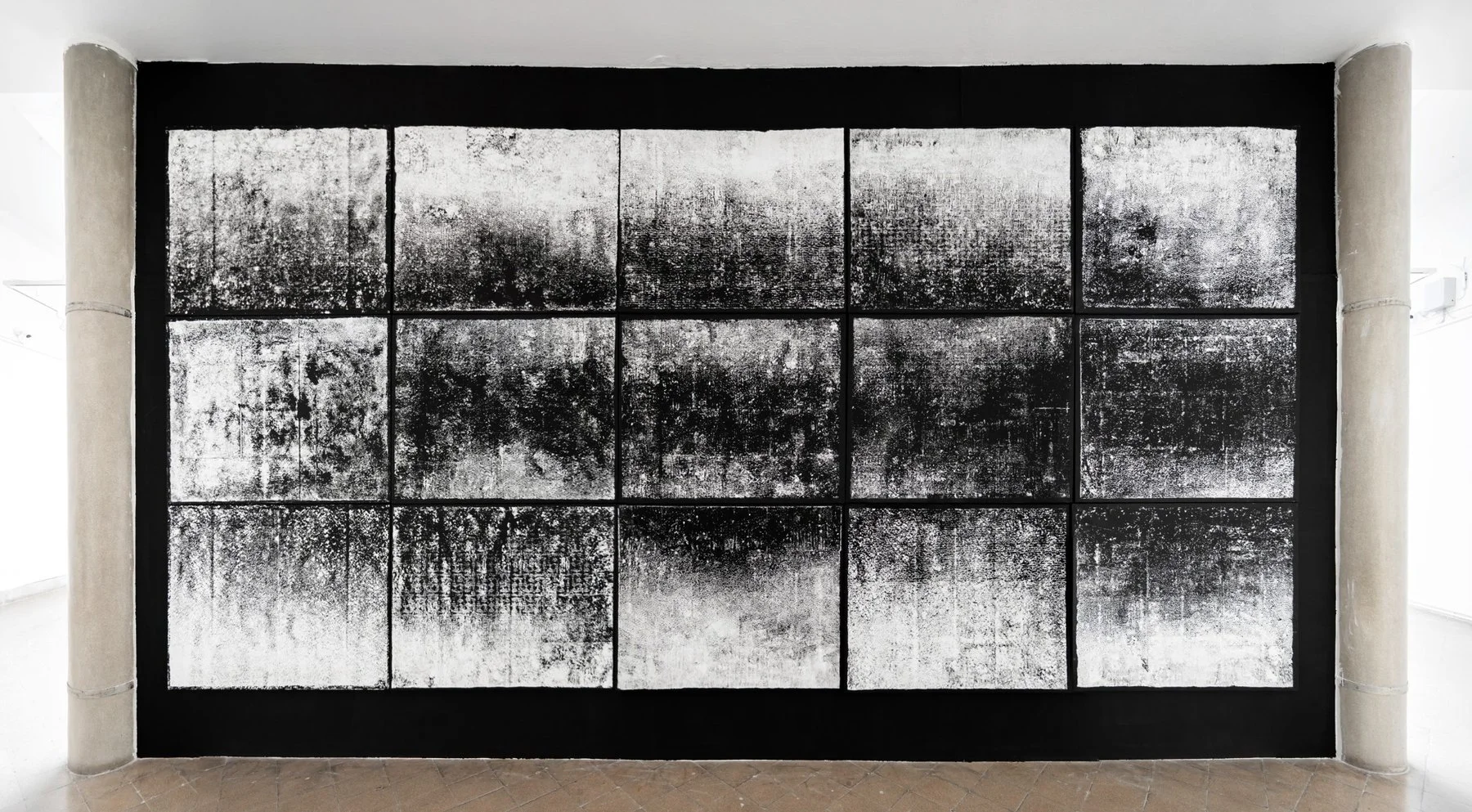 Frontal view of Gábor Koós’s 15-part monotype print installation, reflecting skylight structure and material transformation through light absorption.