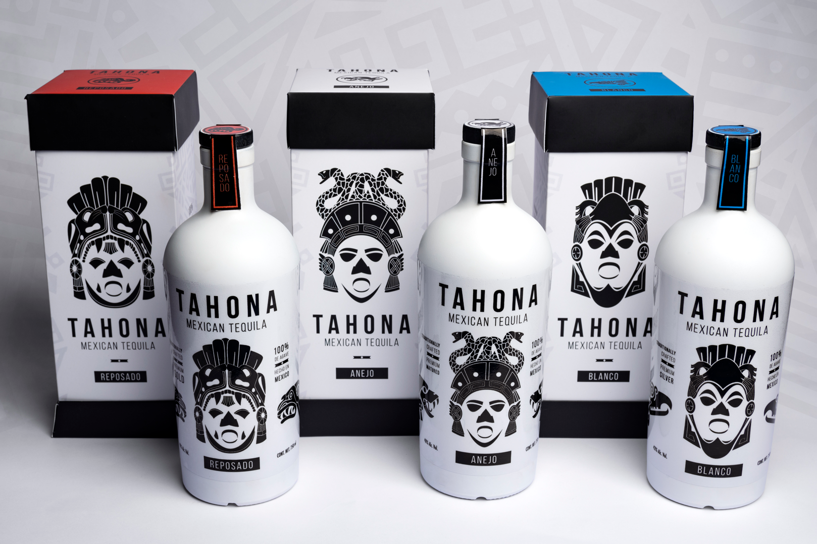 Three bottles of Tahona Mexican Tequila with black and white packaging, each with a different label: Reposado, Añejo, and Blanco, accompanied by matching boxes behind each bottle.