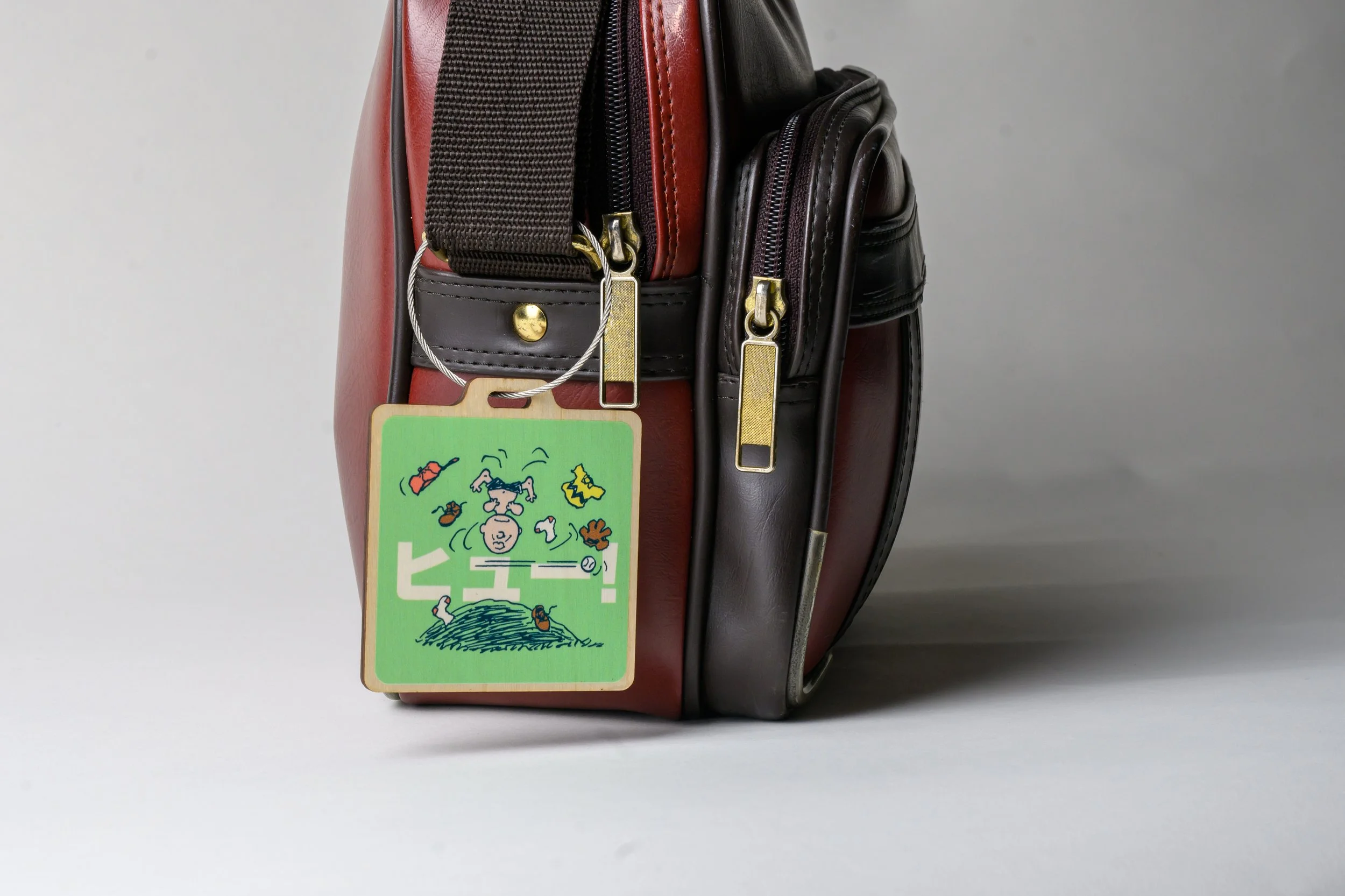 Peanuts humor to your travel gear with this playful Charlie Brown Baseball Toss Wooden Bag Tag! Featuring Charlie Brown mid-flip in a whimsical baseball scene, this eye-catching design captures one of the most iconic moments from the Peanuts comic st
