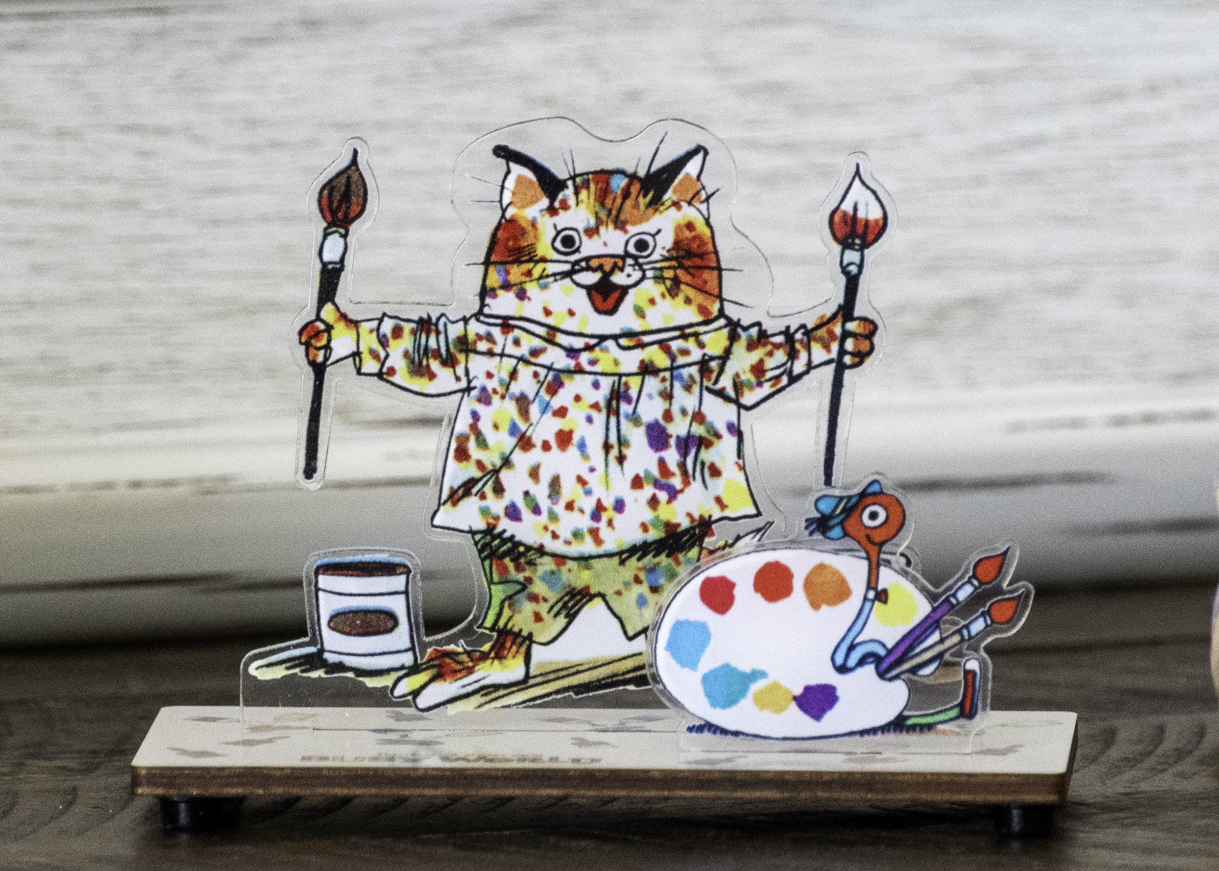 Cartoon figure of a cat dressed as a painter with paintbrushes and an artist's palette.