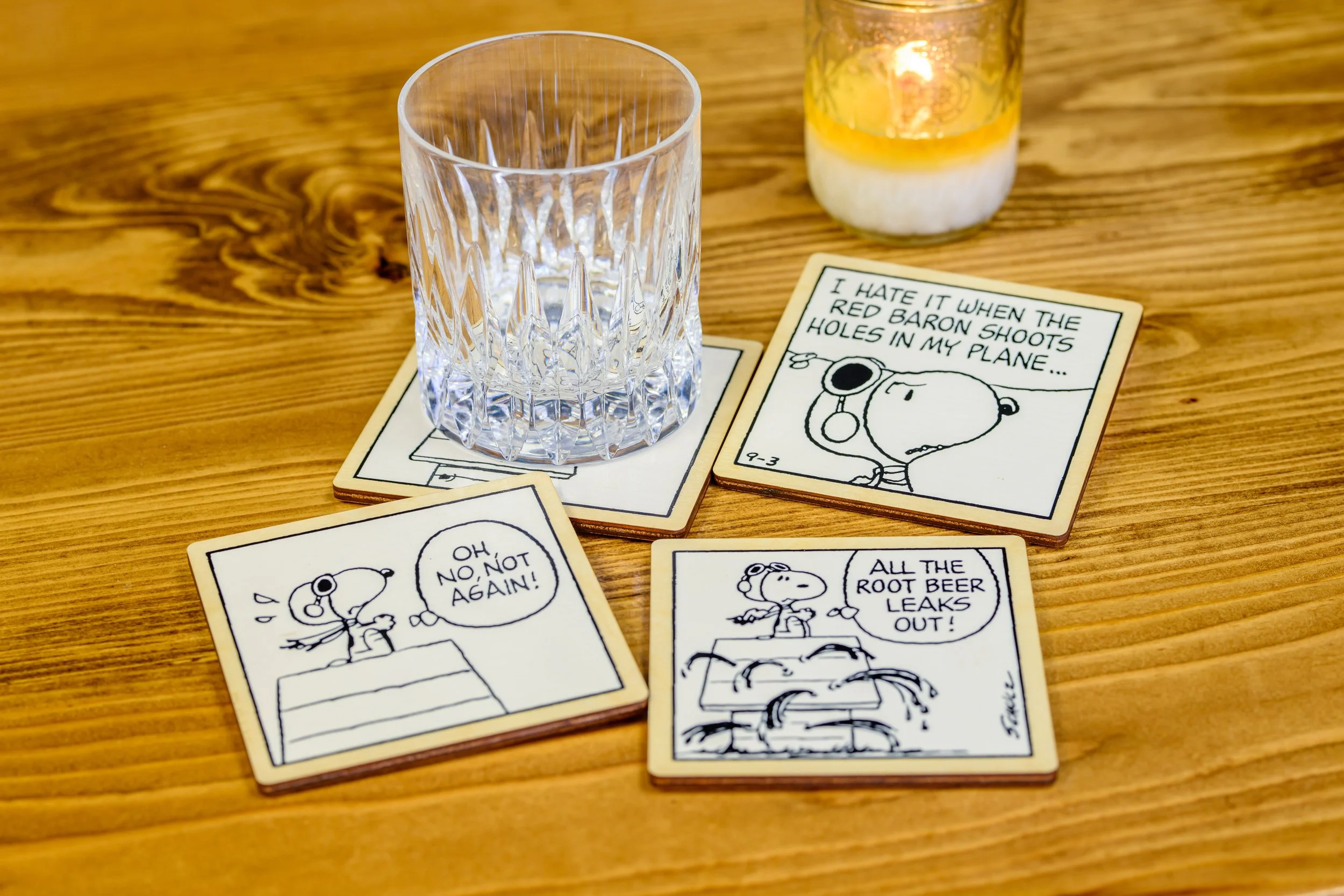 Add a touch of nostalgic charm and humor to your coffee table with this unique Peanuts wood coaster set. Featuring four 3.75" x 3.75" coasters, each one showcases an iconic comic strip from September 3, 1980, where Snoopy, in his role as the Flying A