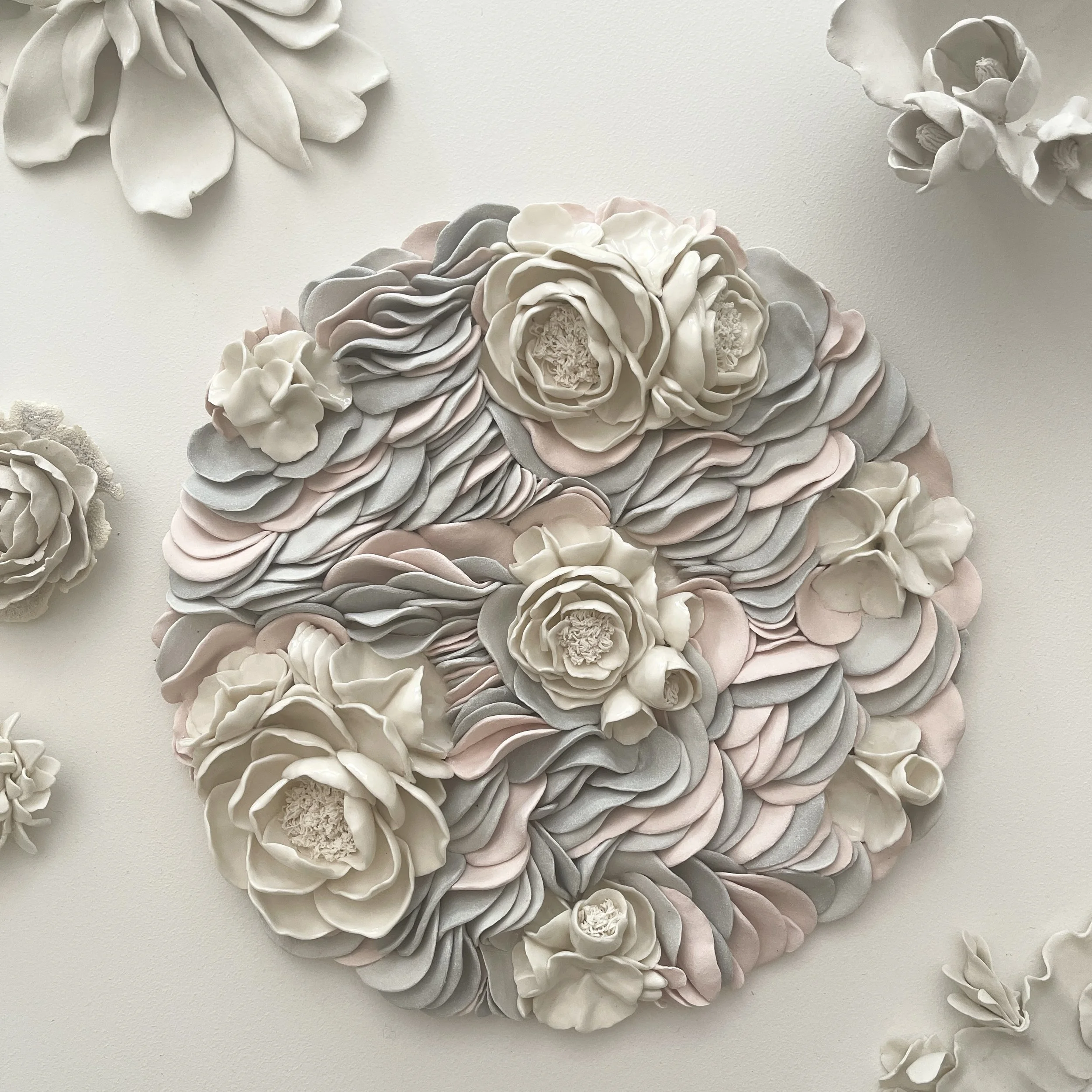 Floral ripples displayed on a contemporary art studio bench, shaowing the scale and sculptural presence of the porcelain wall artwork.