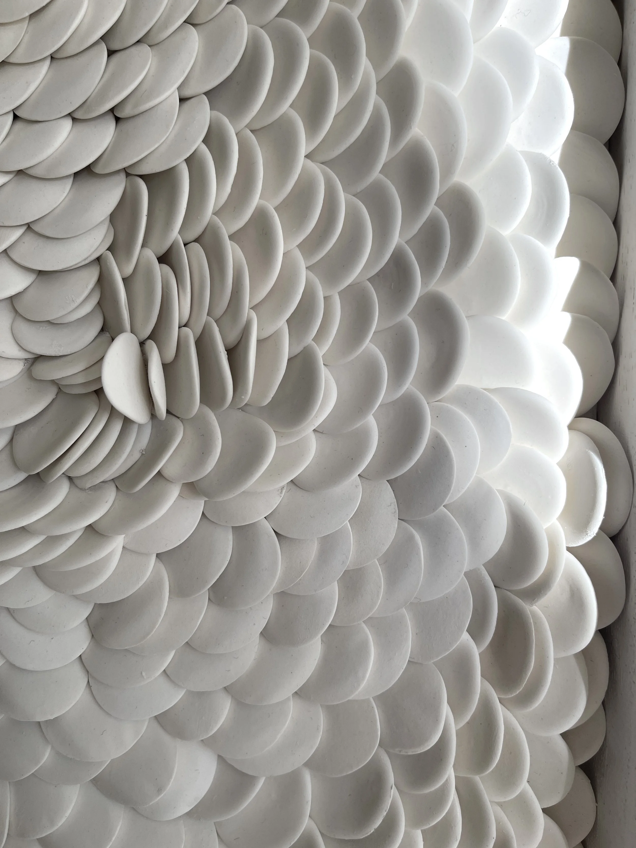 Detailed view of overlapping porcelain forms creating soft transitions between light and shadow.