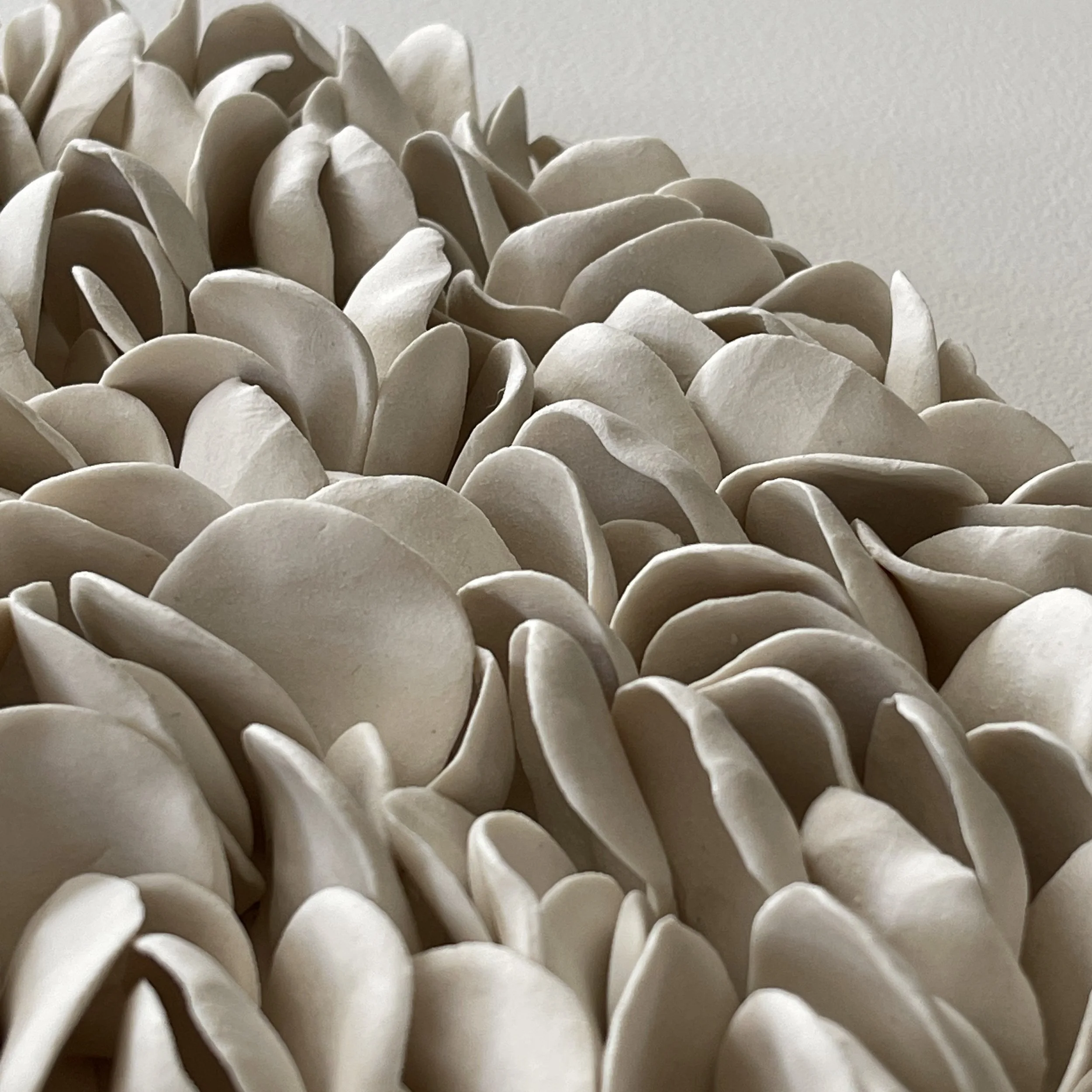 Close up detail of handcrafted porcelain elements showing how light and shade create movement on the wall sculpture.