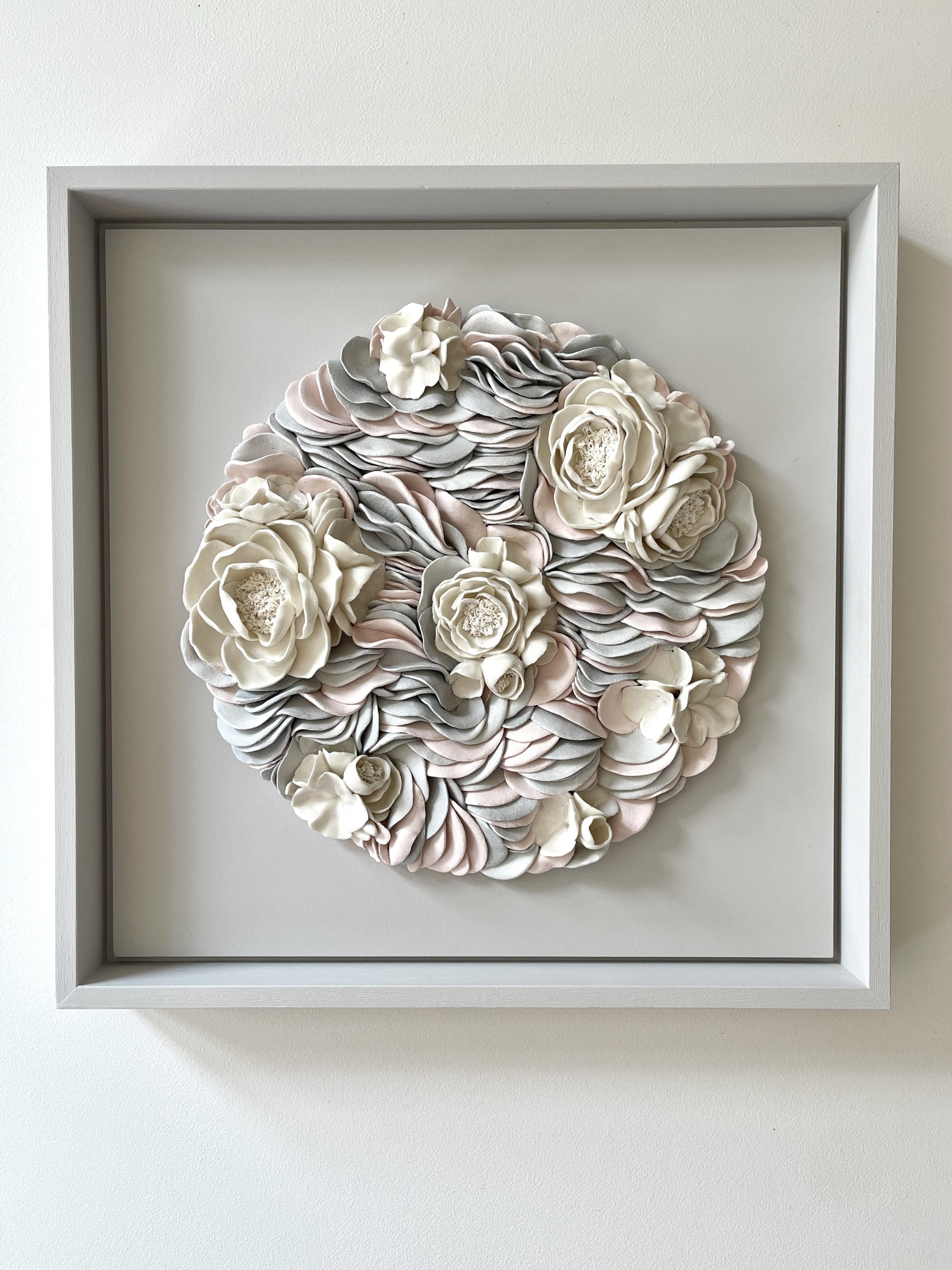 Front view of framed Floral Ripples, a handcrafted wall sculpture composed of individually formed porcelain elements in a layered botanical form.