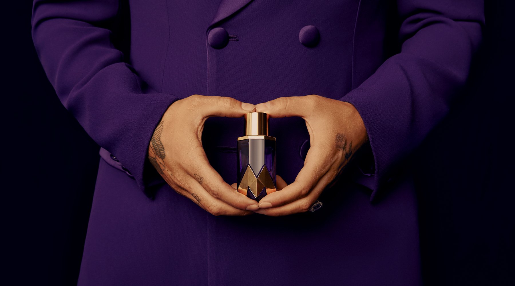 Hands in a purple suit holding the gold and purple Royalty by Maluma fragrance bottle, identity, packaging and photography