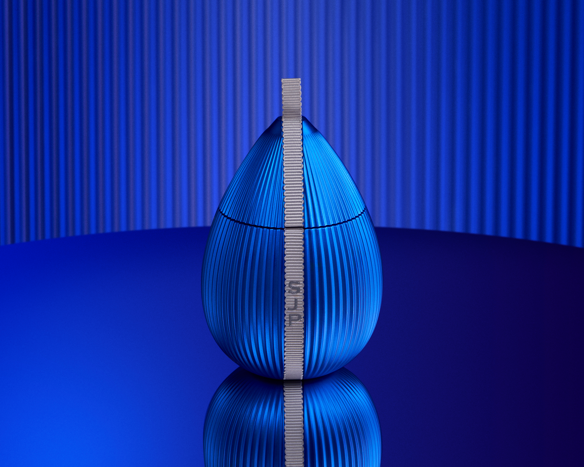 Blue fluted teardrop-shaped packaging with a grey SJP ribbon, Sarah Jessica Parker packaging, digital design, photography and video
