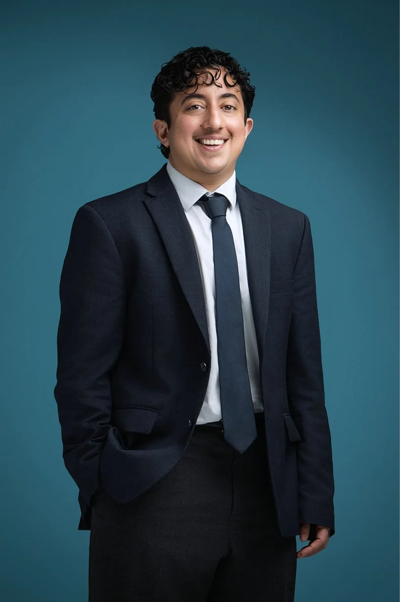 Lucas Marqus in a dark navy blue suite, blue tie and white dress shirt.