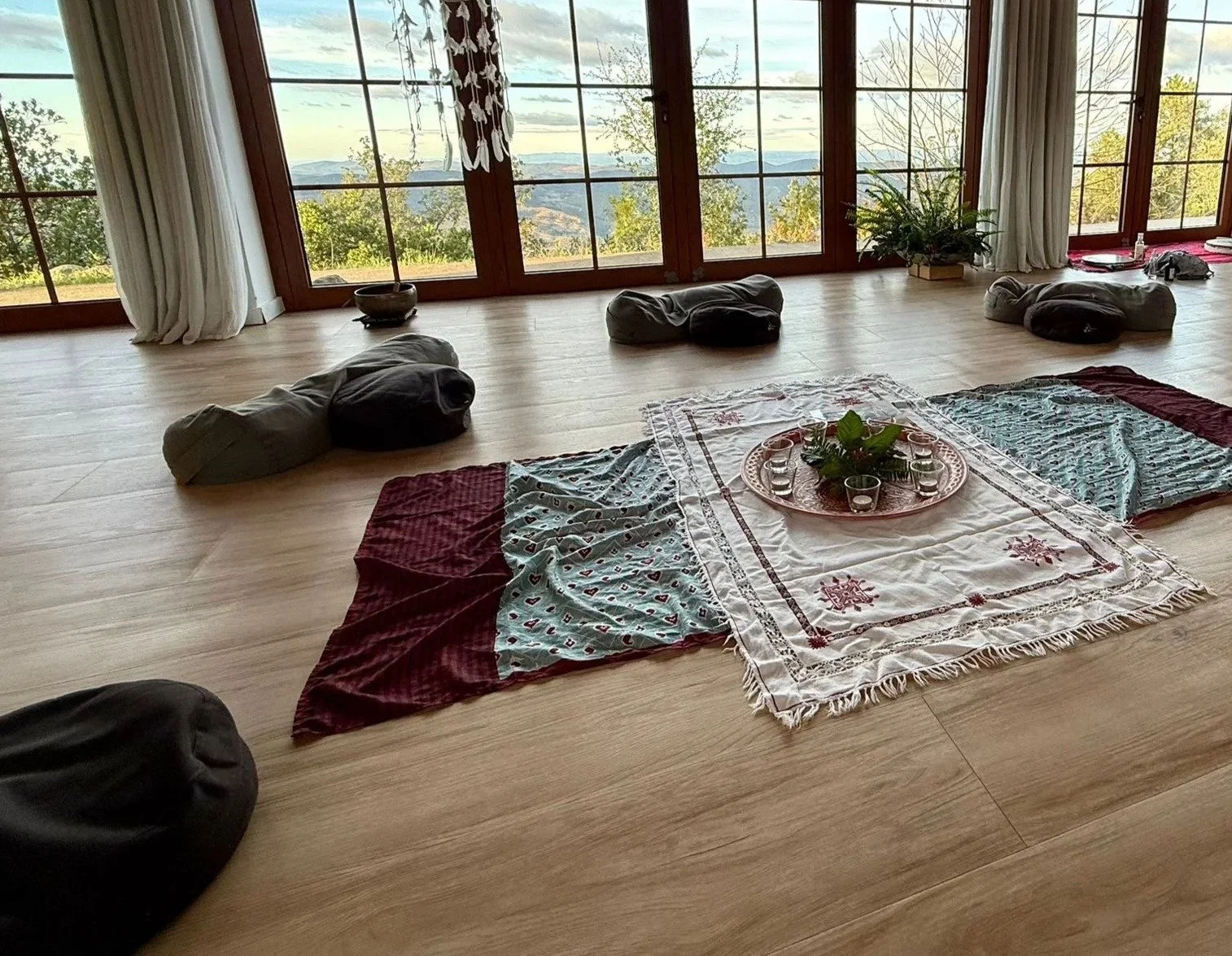 indoor retreat environment with multiple blankets on the ground and glasses in the middle