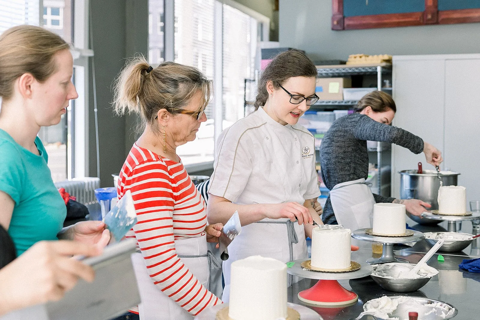 Cake Decorating workshop at Honey Crumb Cake Studio featuring instructor showing students how to frost a cake with buttercream