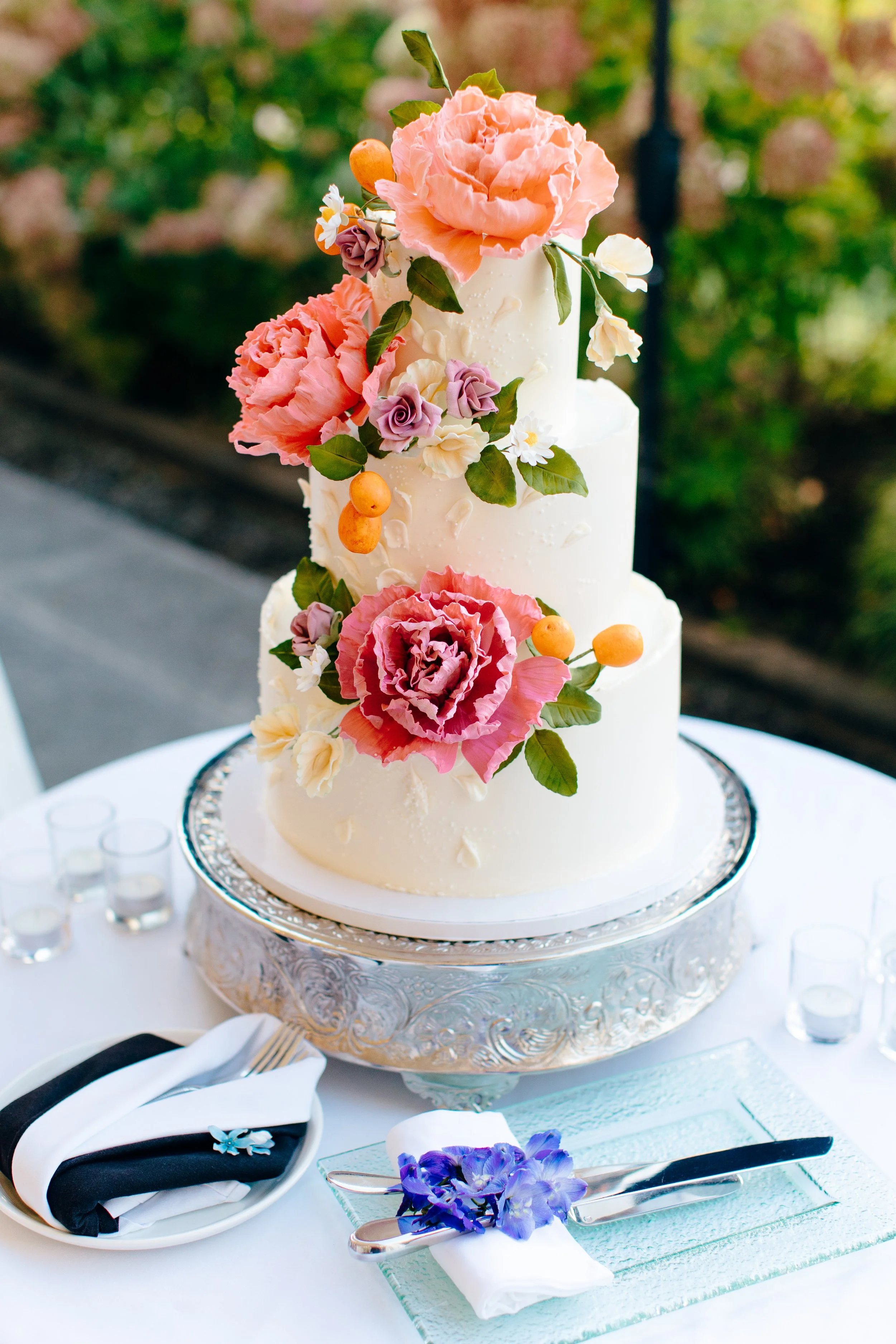 Romantic and fun buttercream wedding cake with hand sculpted sugar flowers and citrus fruits in a colorful palette. Image courtesy of Cameron Zegers Photography