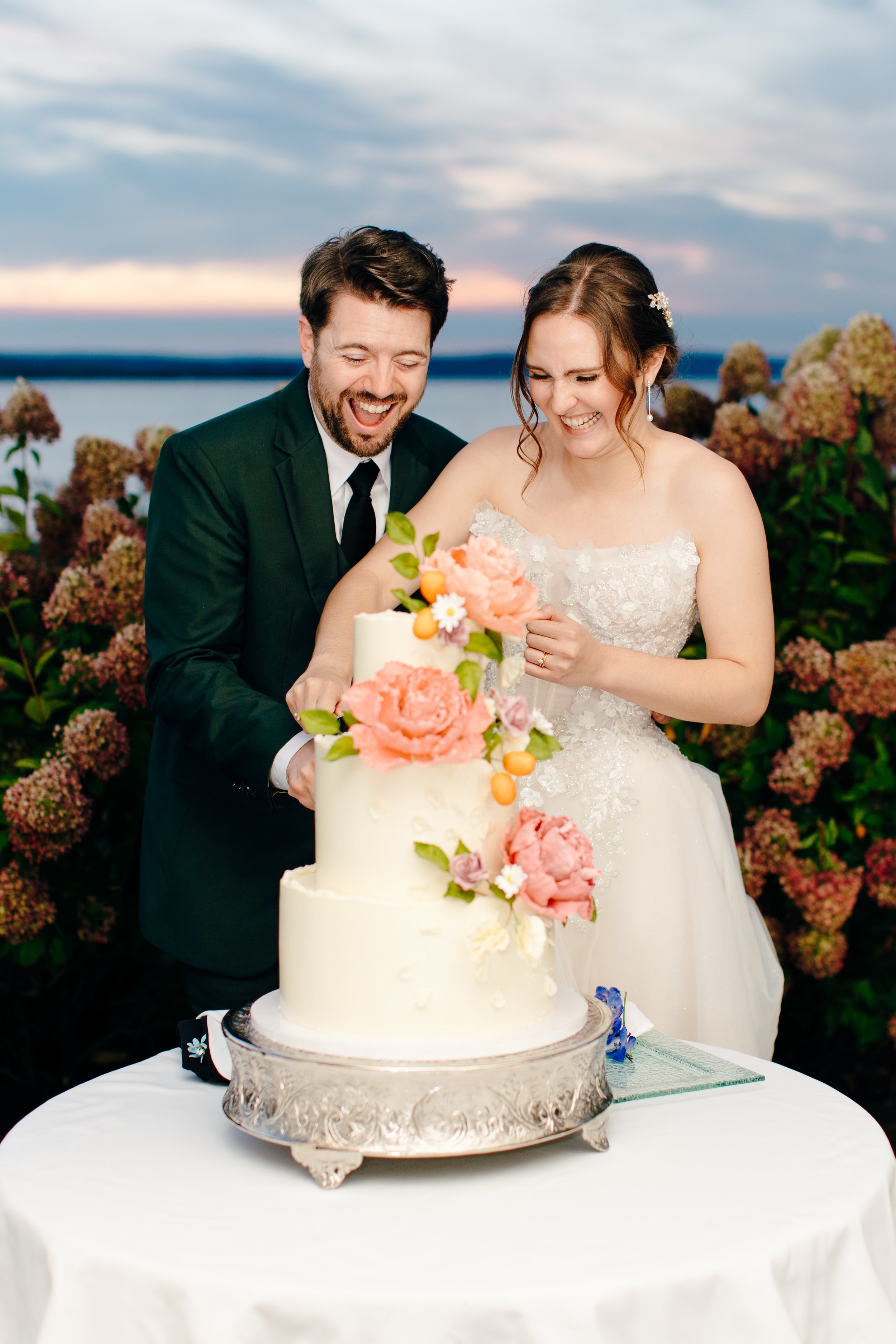 Couple cutting into their romantic and fun buttercream wedding cake with hand sculpted sugar flowers and citrus fruits in a colorful palette. Image courtesy of Cameron Zegers Photography