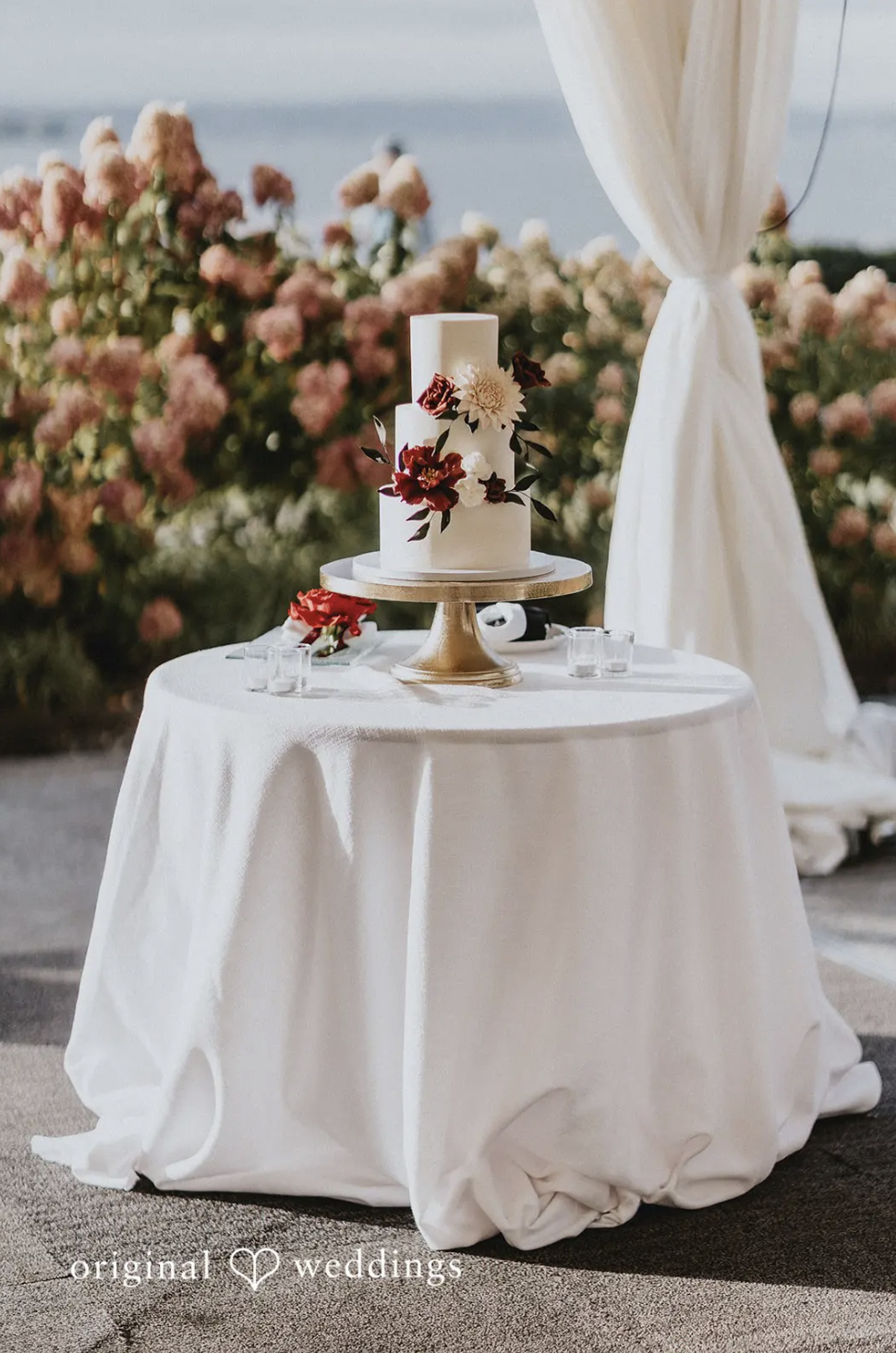 Three tiered buttercream cake with handmade sugar flowers in burgundy and blush. Image courtesy of Original Weddings
