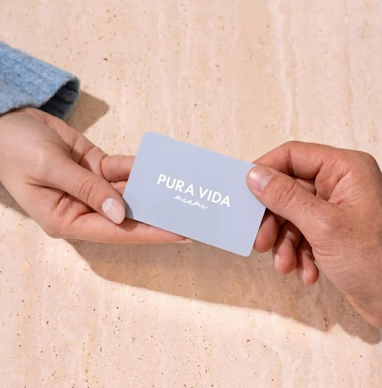 Two hands holding a Pura Vida Miami gift card