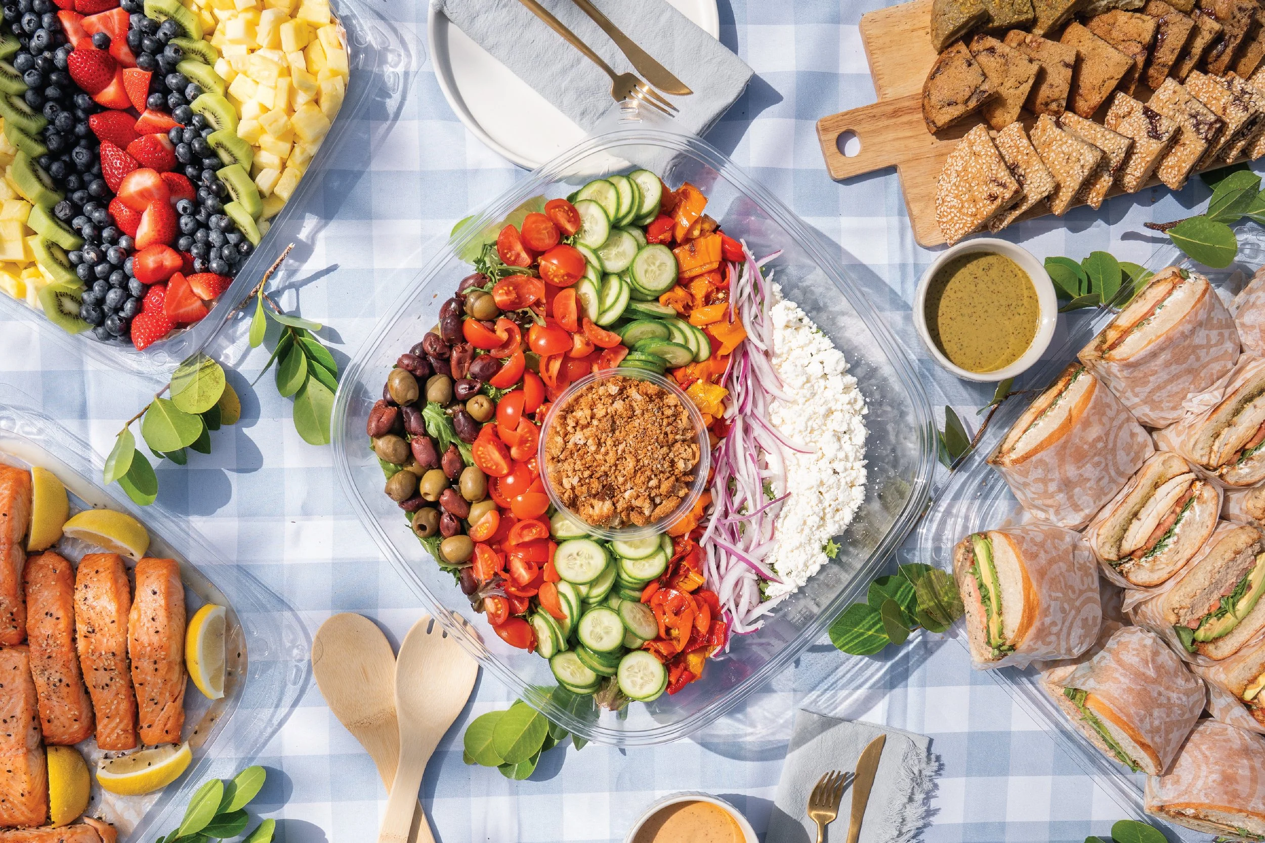 Catering table spread with a salad, fruit, and sandwiches.