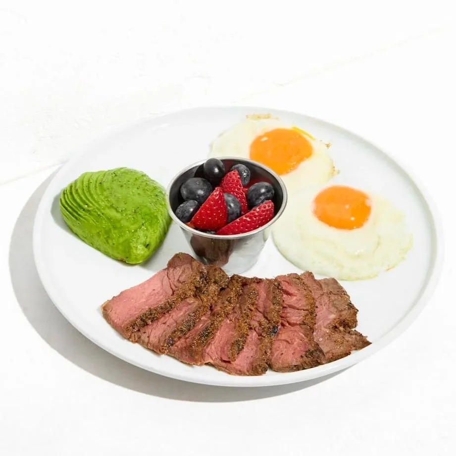 Breakfast platter with grass-fed steak, avocado, over easy eggs and mixed fruits