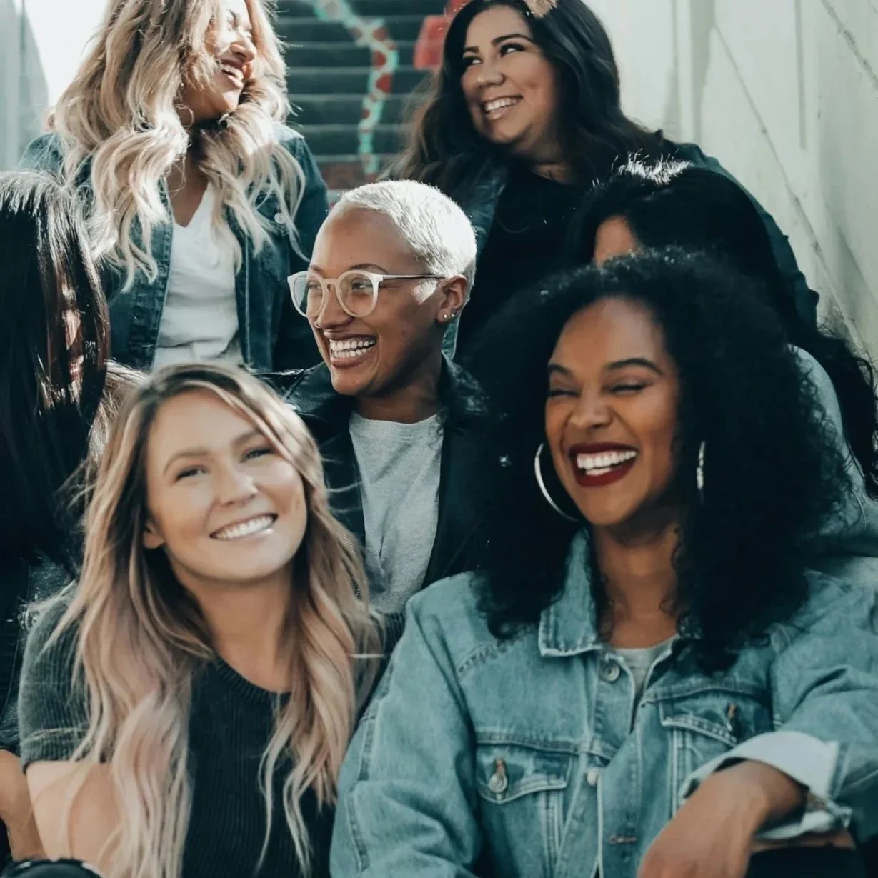 Group of diverse women smiling and laughing together indoors.