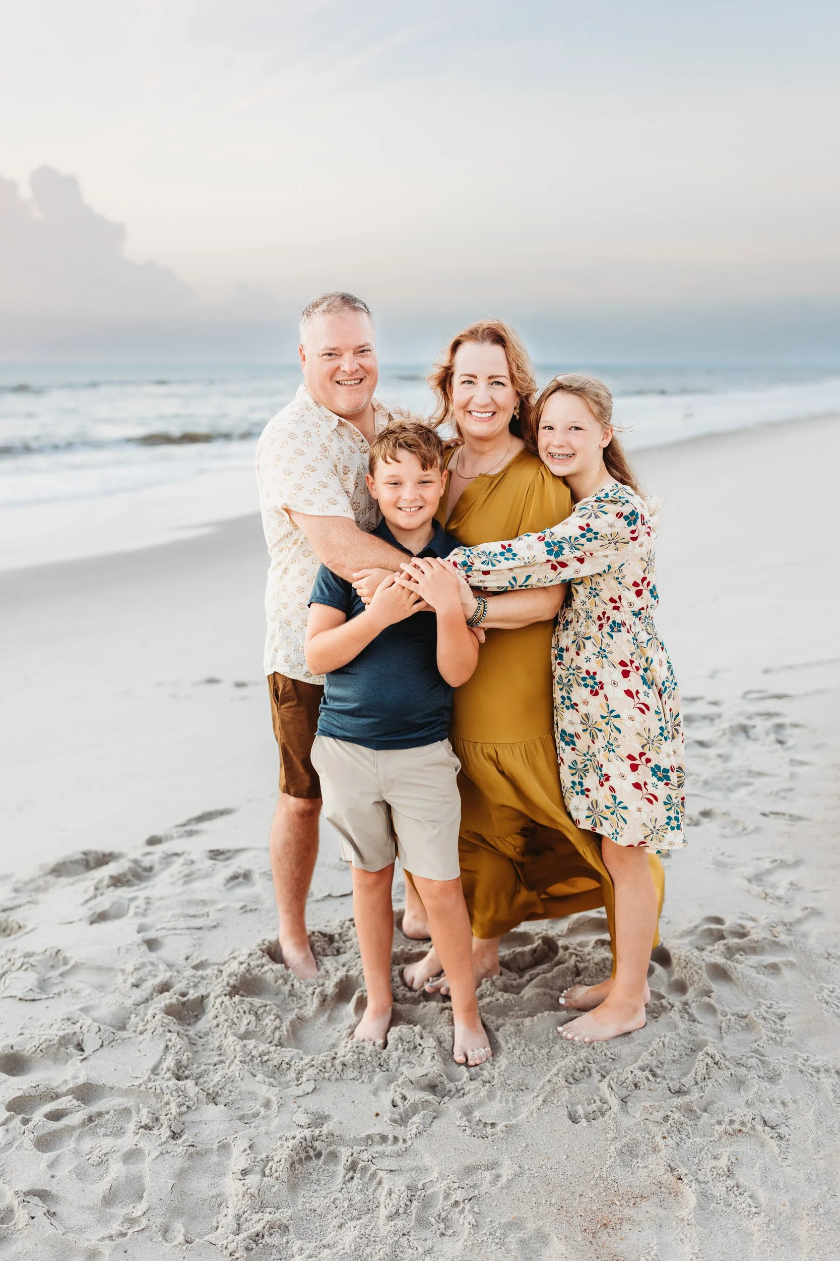 family portrait at sunrise on the beach with pretty pastel clouds
