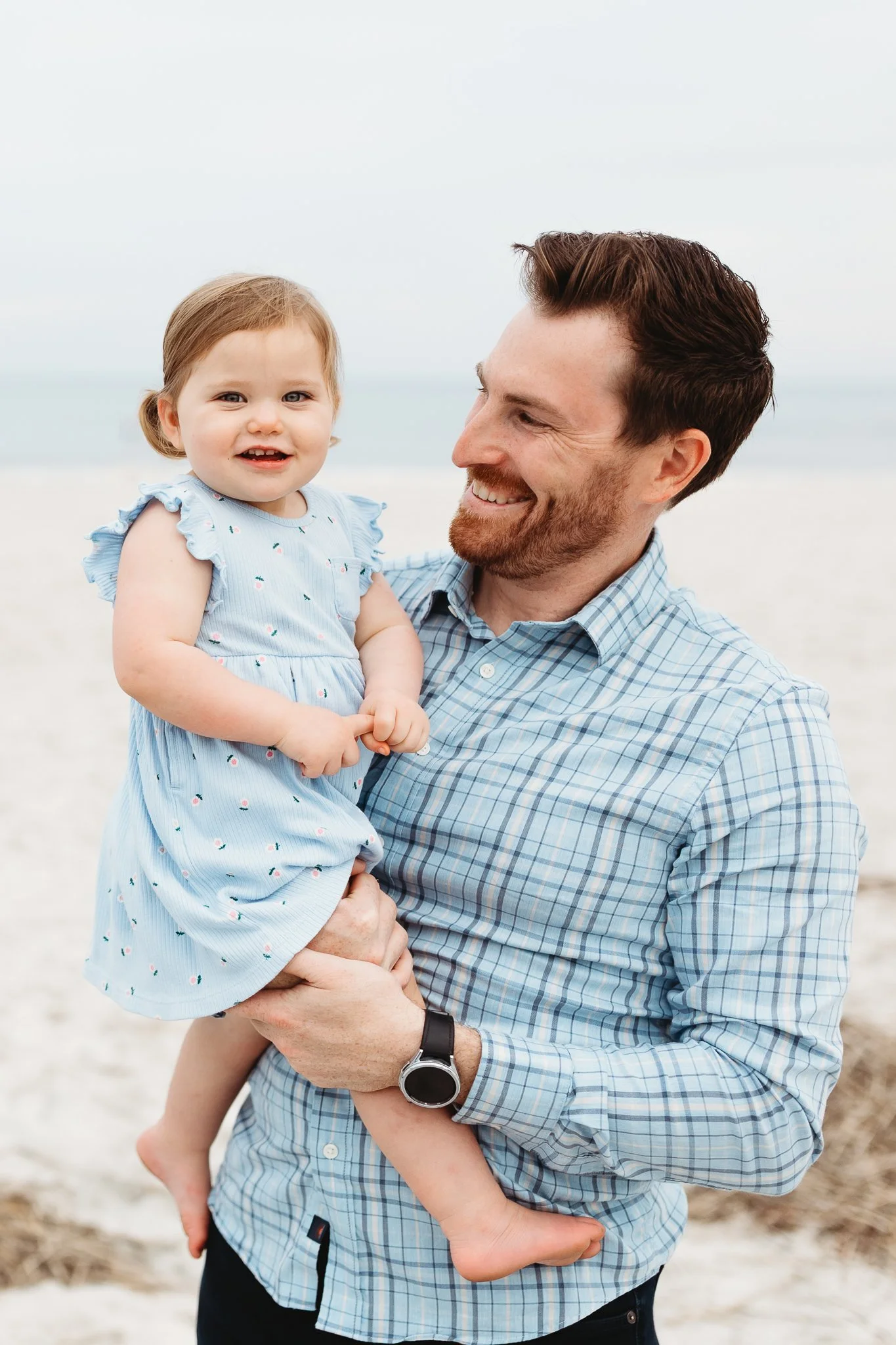 dad holding baby daughter and looking at her and she is laughing