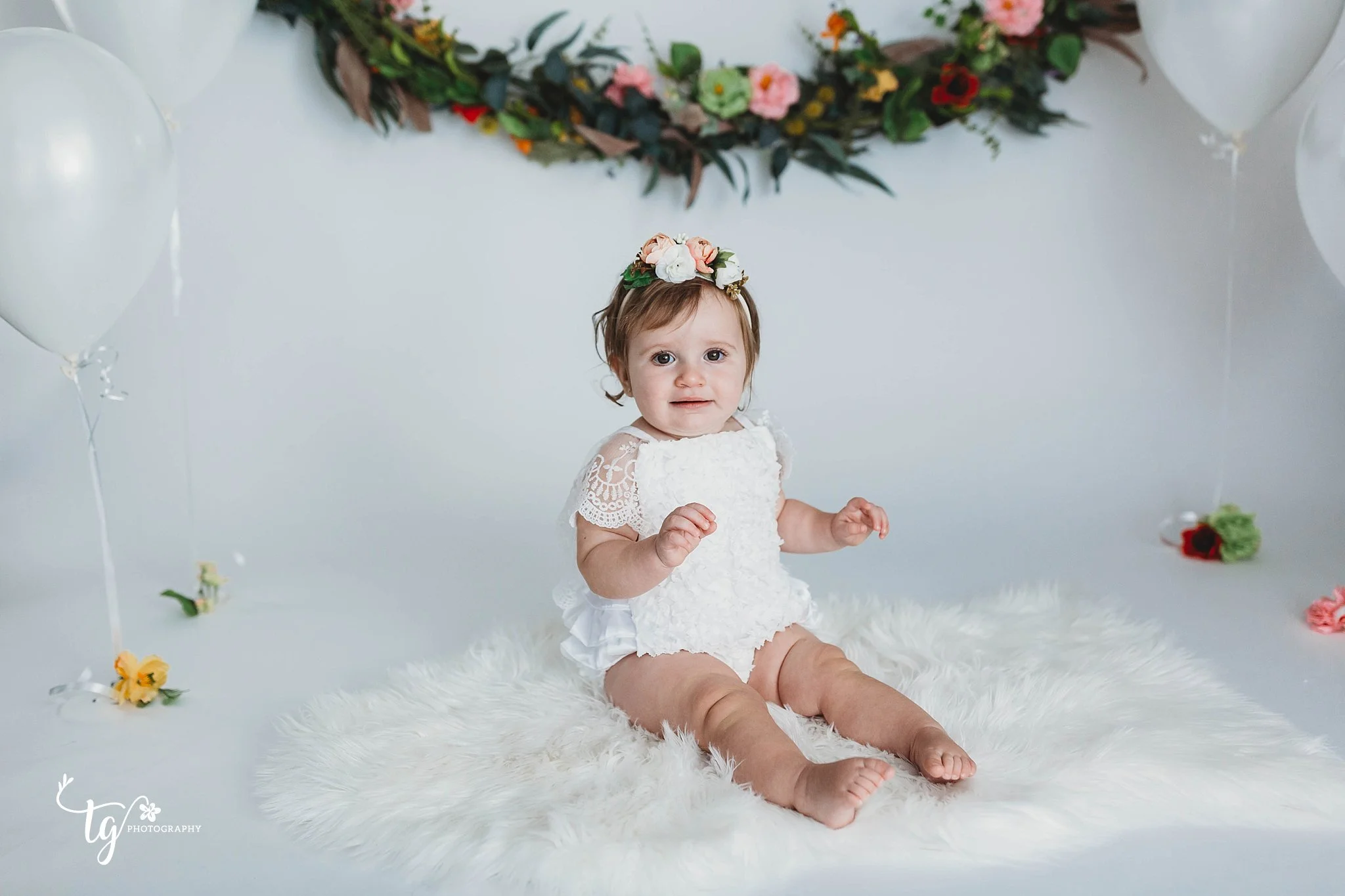 little girl in a boho white lace romper on a white set for birthday photos