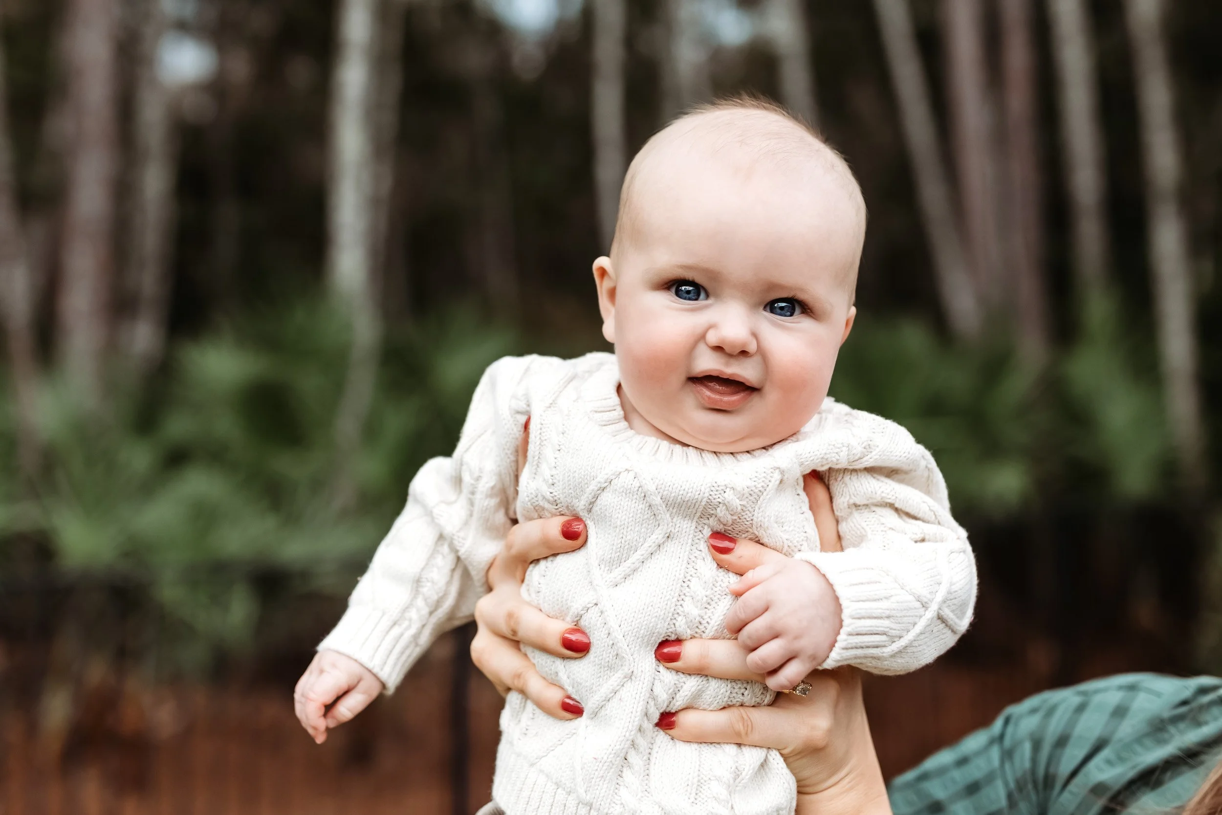 baby boy in a backyard in Jacksonville and he is laughing while his mom holds him high 