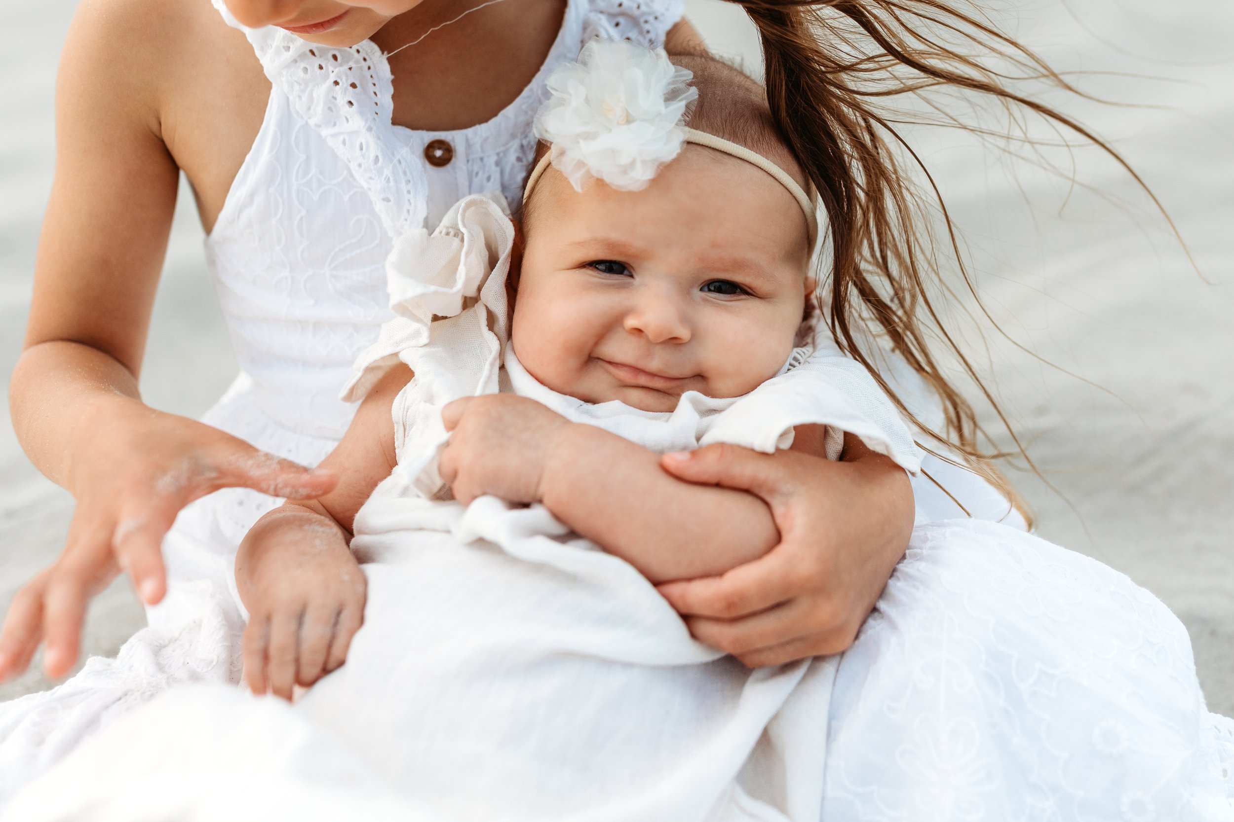 close up of baby smiling in sister's arms