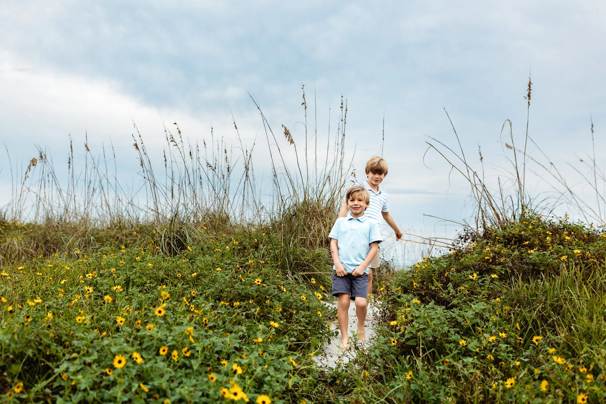 boys walking down a path with sticks in their hands during family photos at Anastasia state park