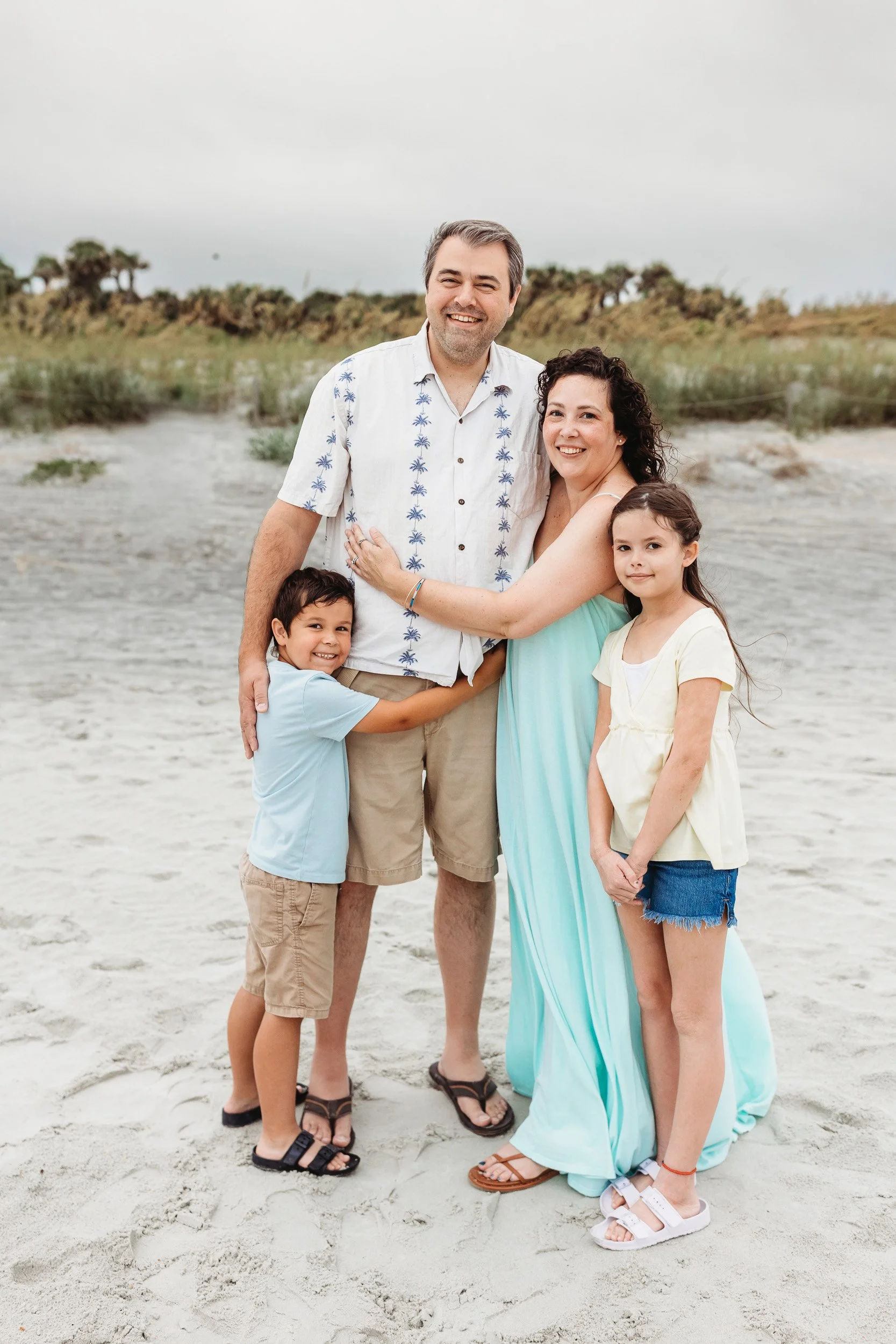 family in yellow and teal for a family photo on the beach at sunrise