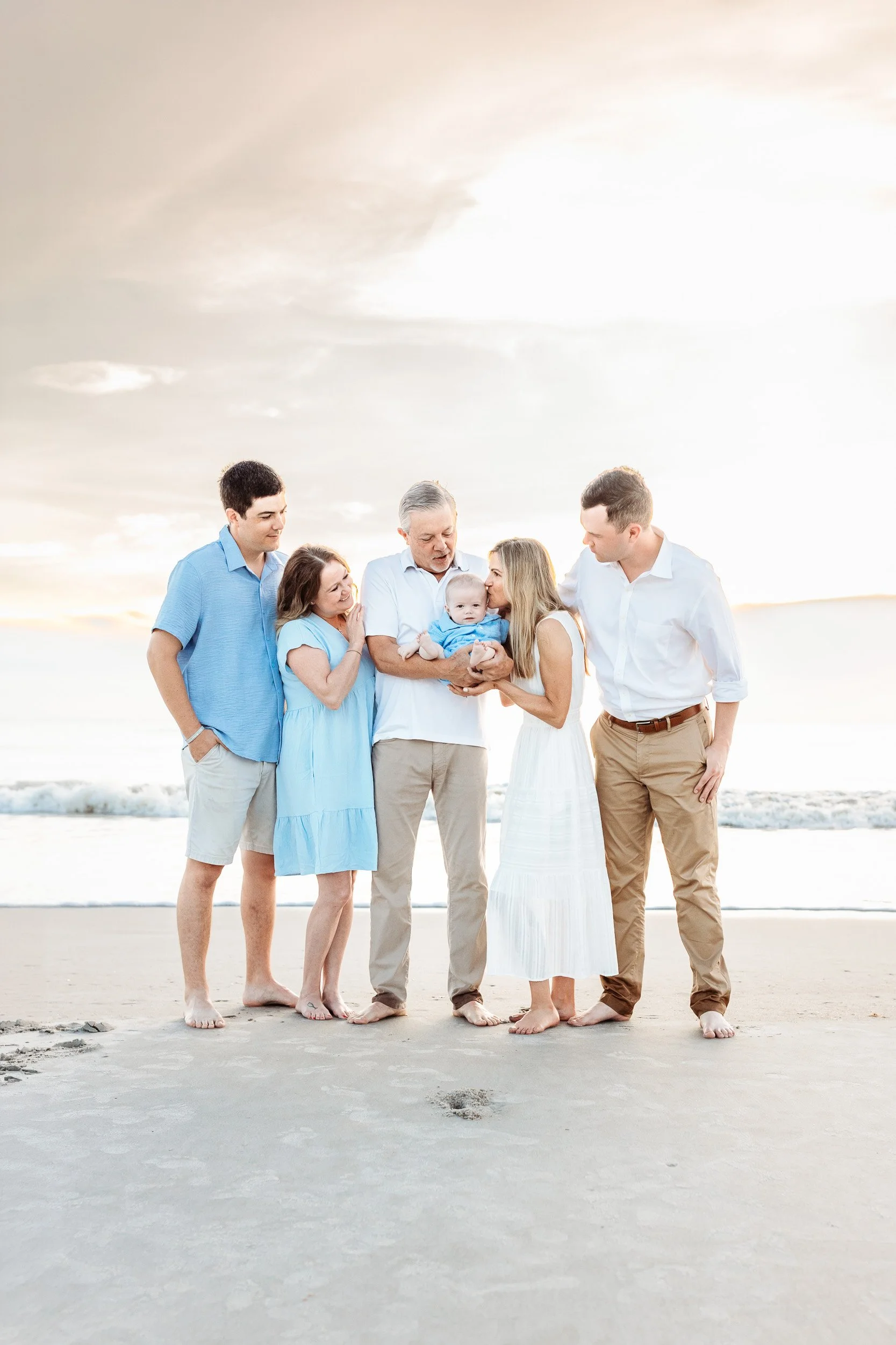 artistic image of a family embraced on the sea shore at sunrise and grandma is kissing the grandchild