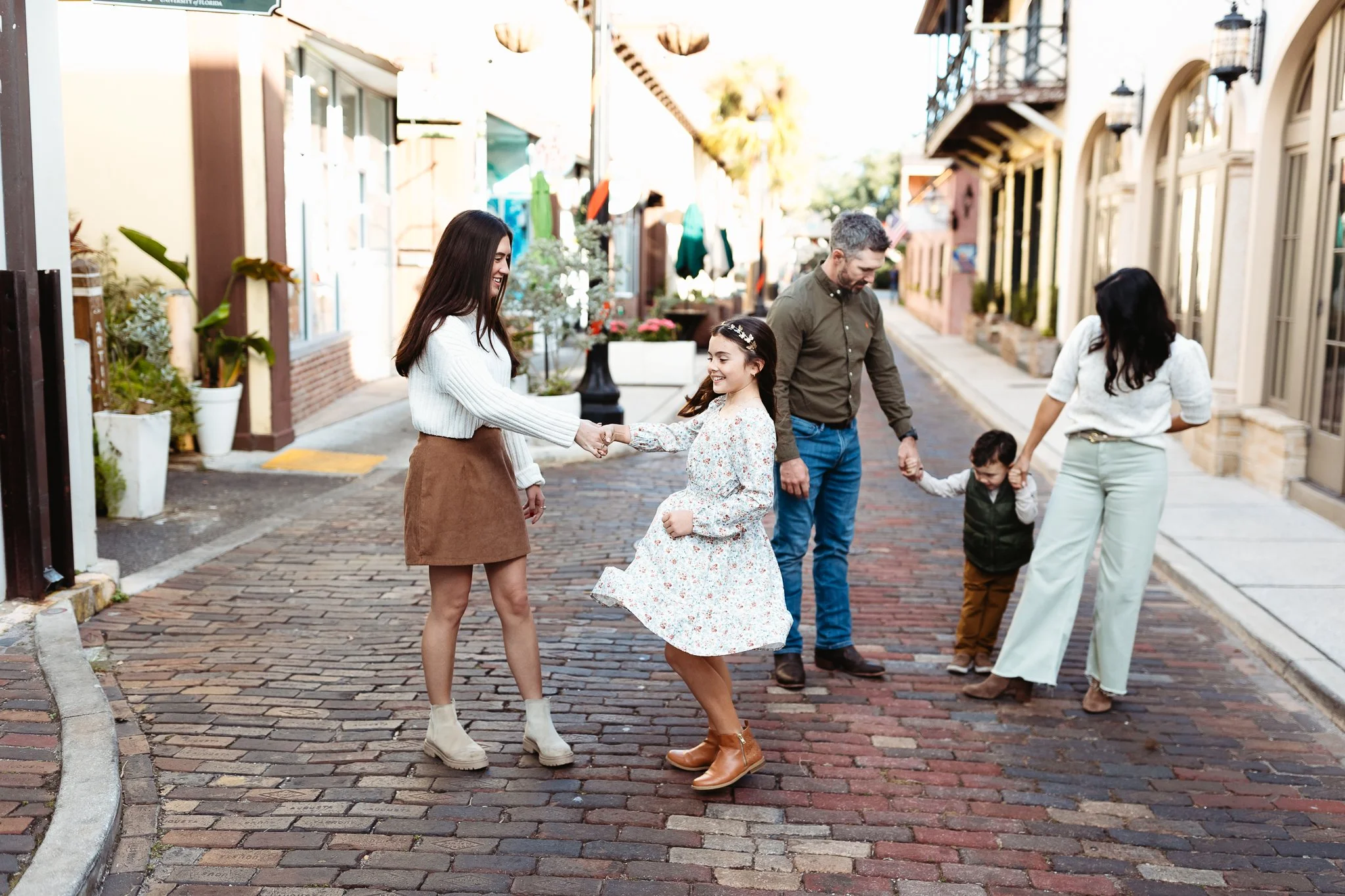 sisters dancing in the street while parents walk with younger brother