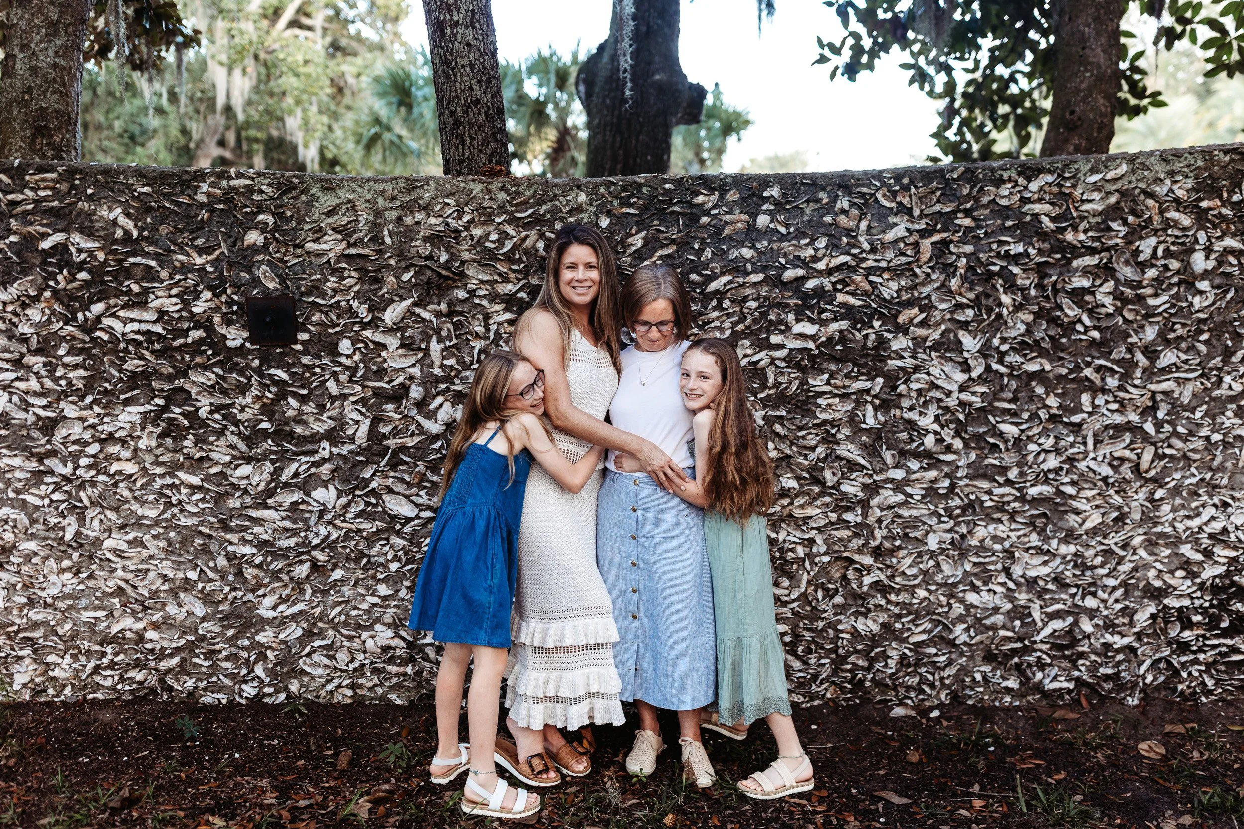 mother, grandma and granddaughters embraced in front of a coquina wall by the fountain of youth in st augustine during family photos