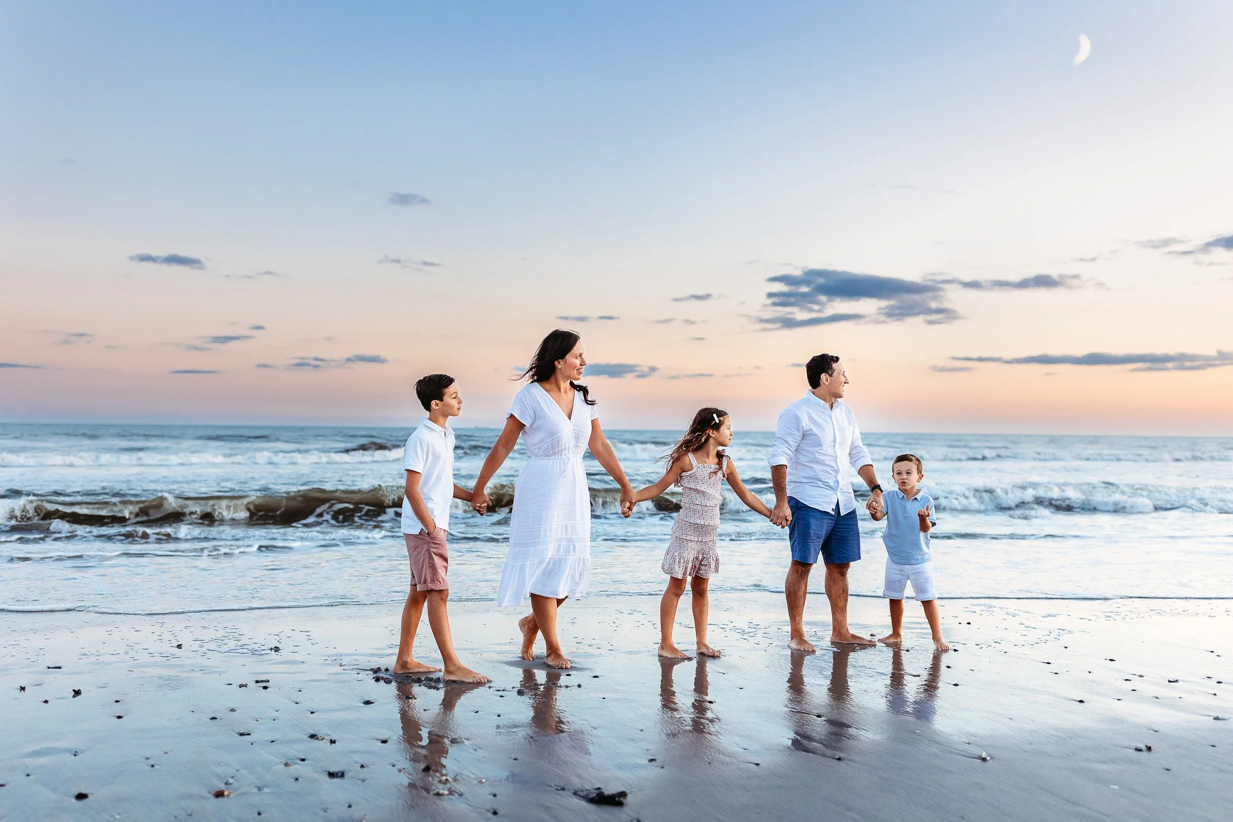 family walking single file with the moon out and pink and blue sunset sky