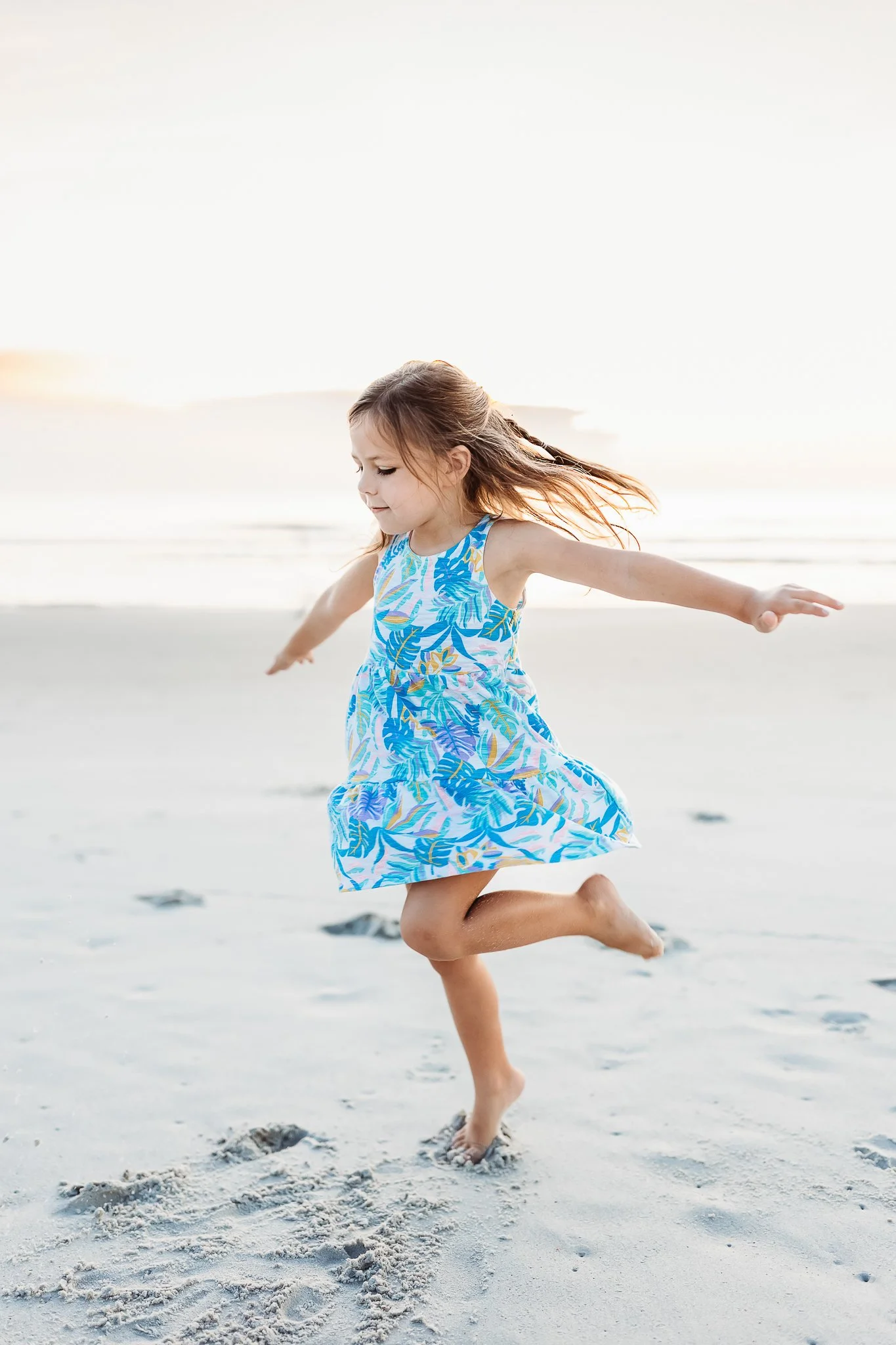 little girl spinning on the beach at sunrise for family photos during vacation