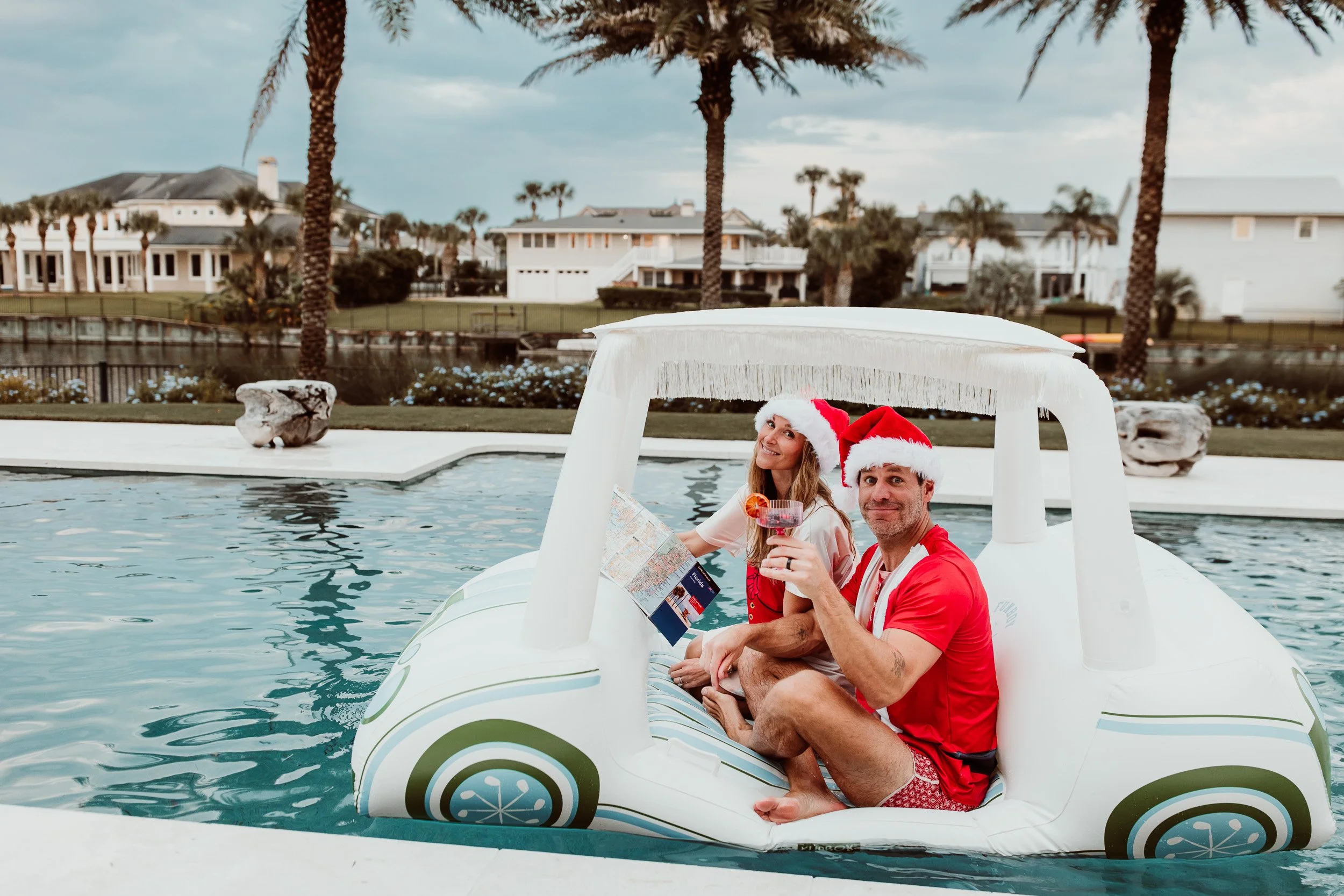 husband and wife in an inflatable golf cart float and mom is reading a map while dad sips a cocktail