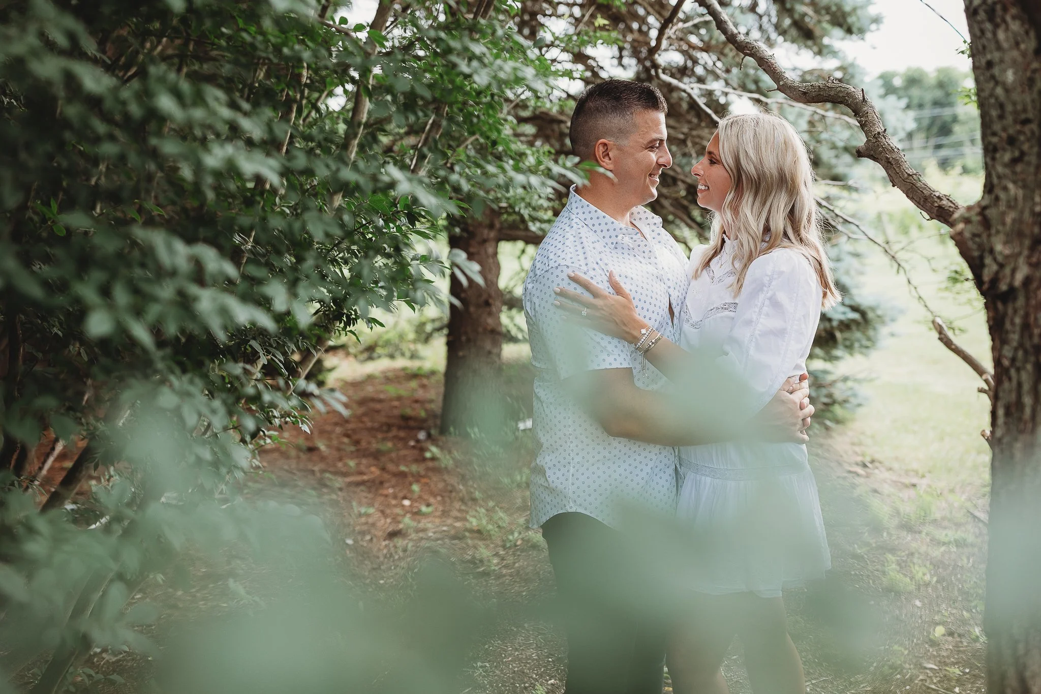 couple photographed through leaves after getting engaged