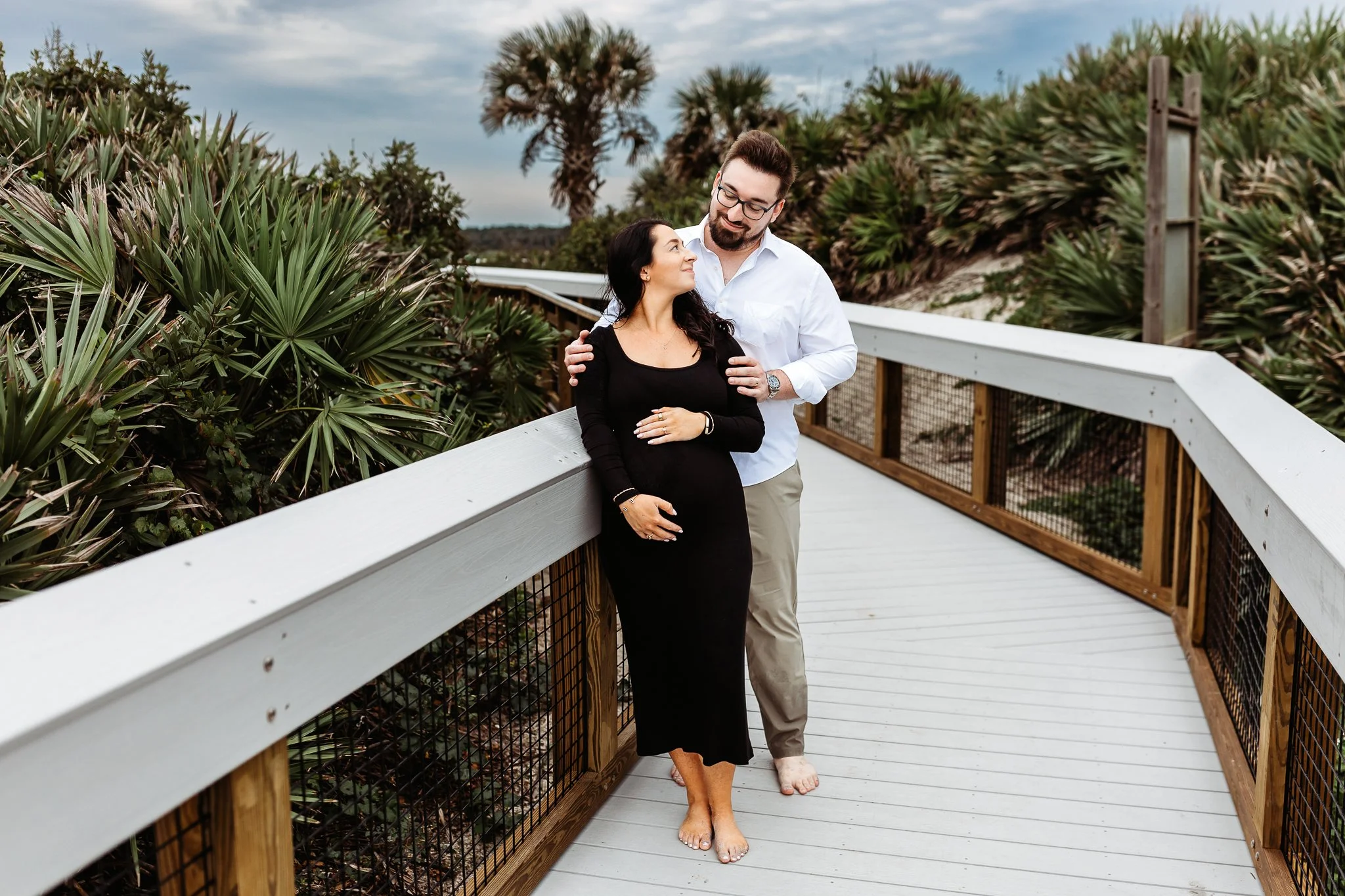 Expecting parents holding each other close during maternity portraits at Guana North.