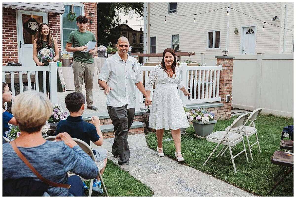 couple laughing after getting married in their yard and walking down the aisle