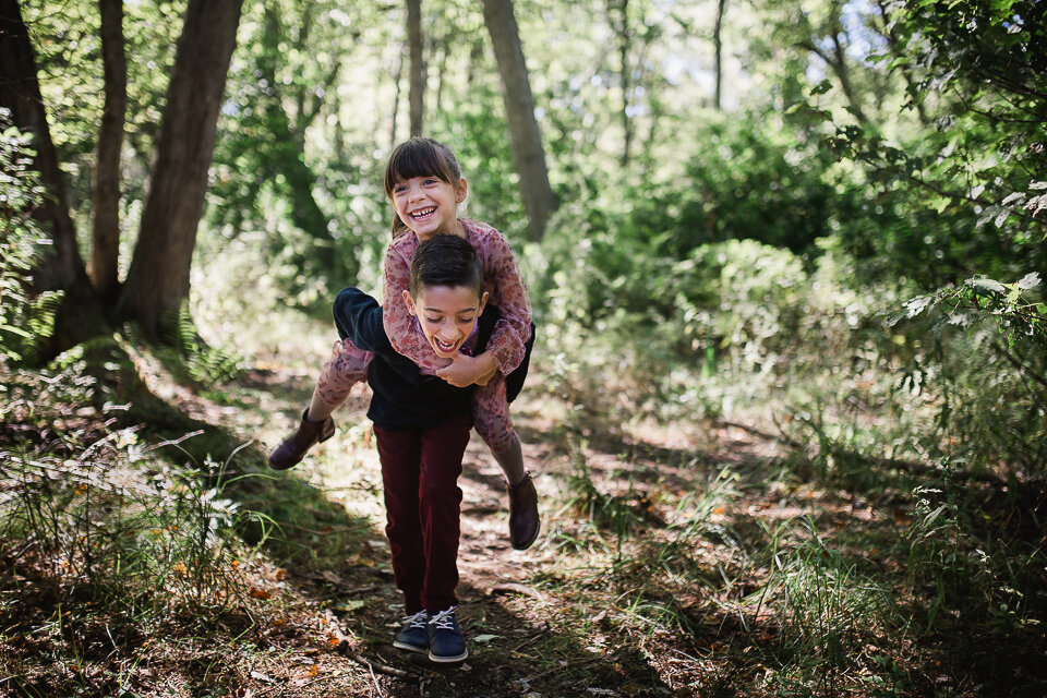 siblings piggy back in park