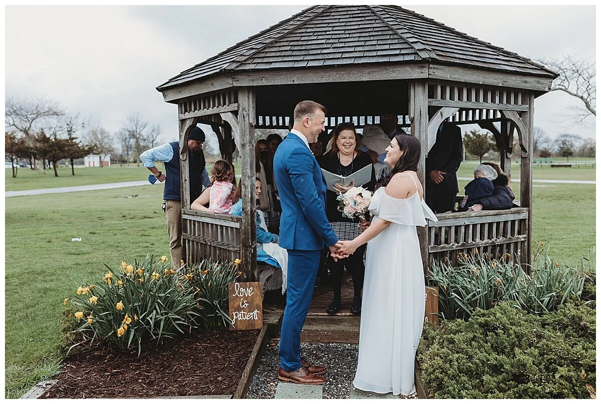bride and groom in front of a gazebo during vows with officiant