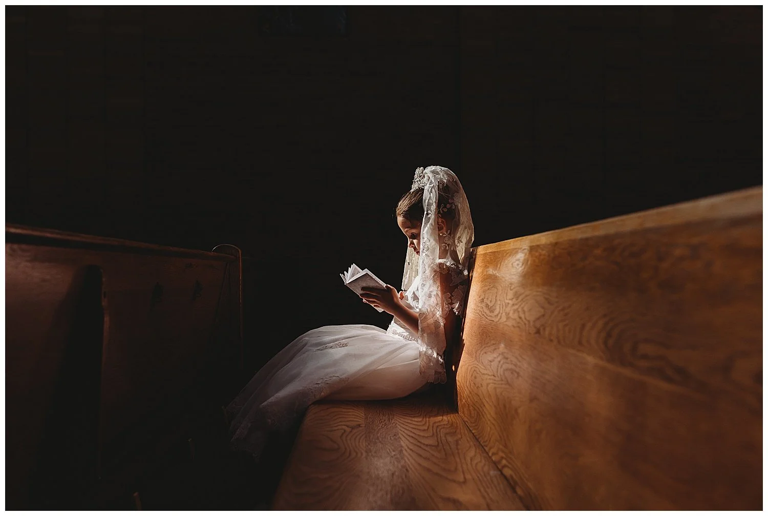 girl state Dina church pew with dramatic light on her while she reads her bible