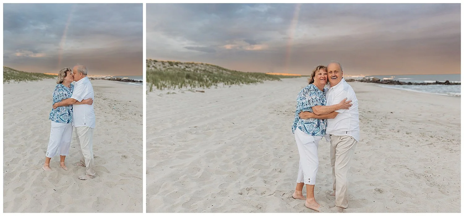 grandparents embraced and kissing with rainbow behind them and pink sky on the beach