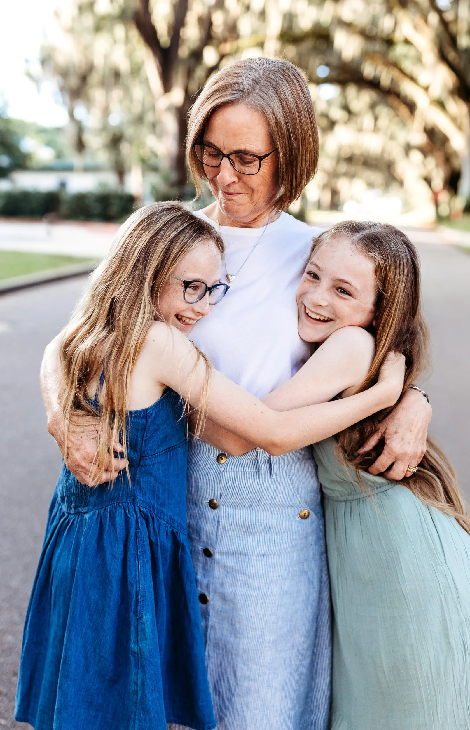 grandma with her twin granddaughters embraced on magnolia ave in st augustine for family photos