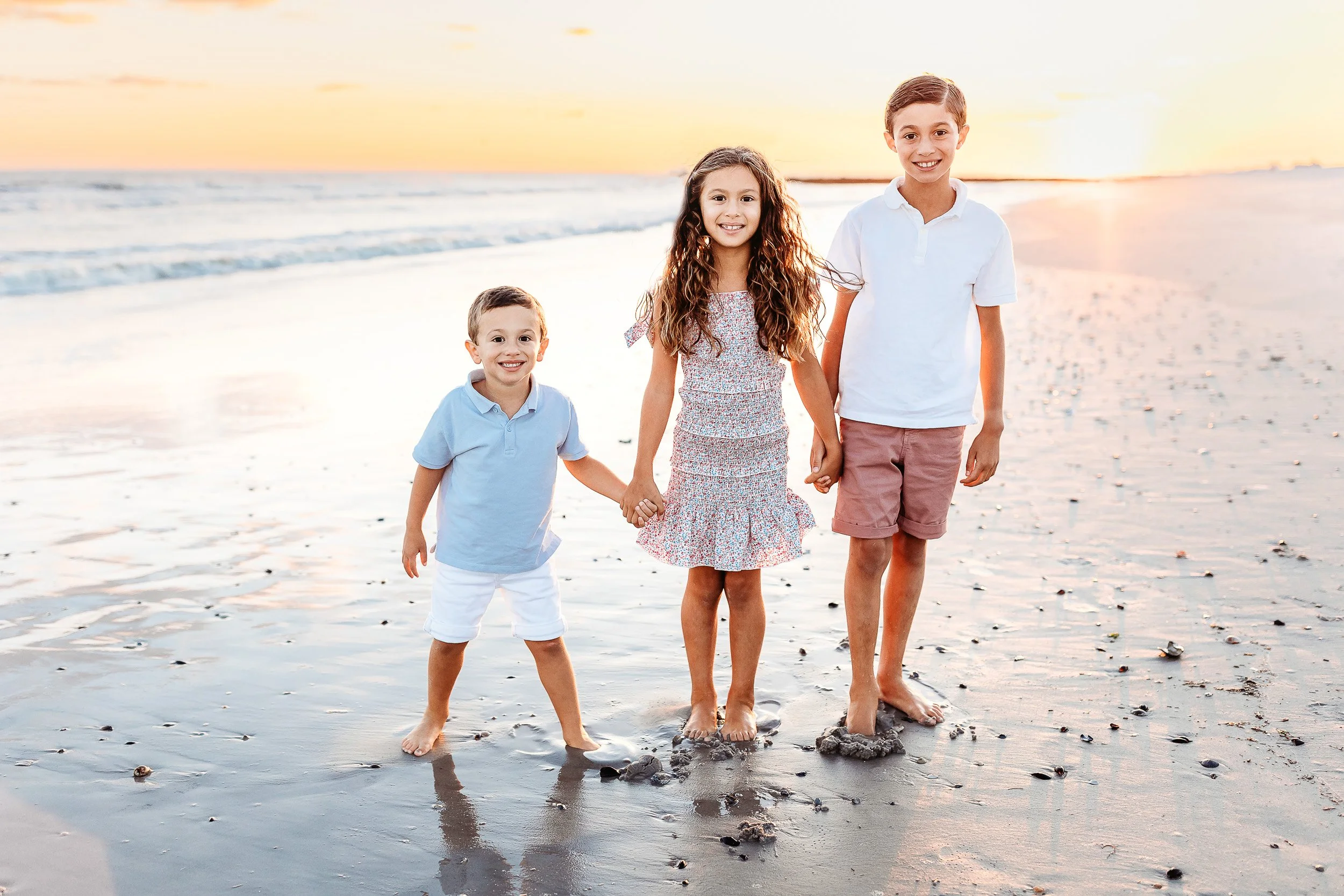 children on the beach in st augustine at sunset for family photos and they are holding hands