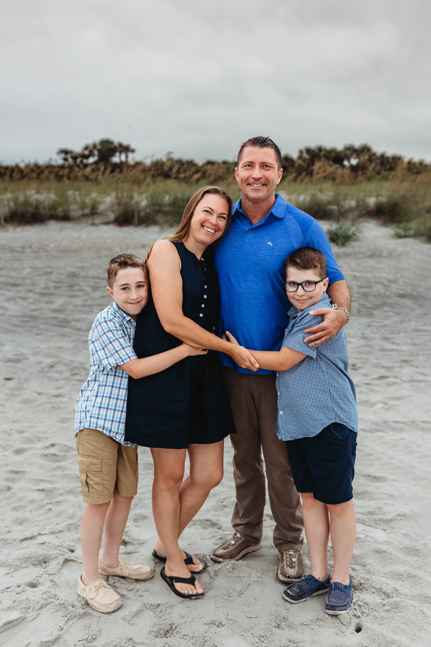 family in navy and blue for a family photo in front of a dune