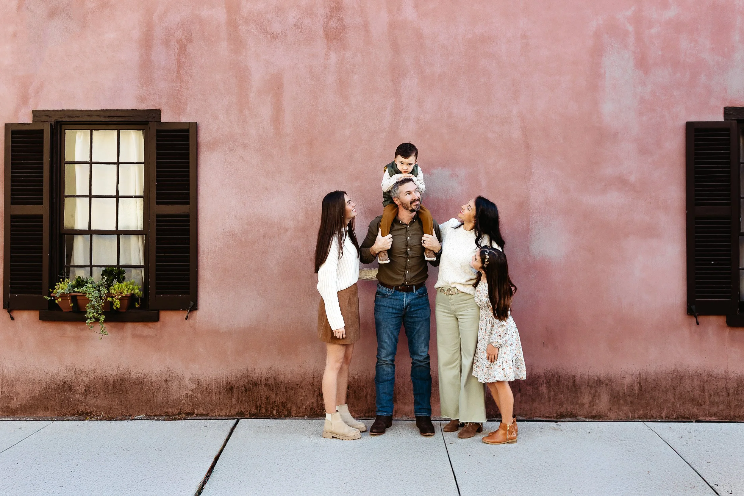 family in front of a pink building in historic st augustine during a vacation and they are getting family photos taken