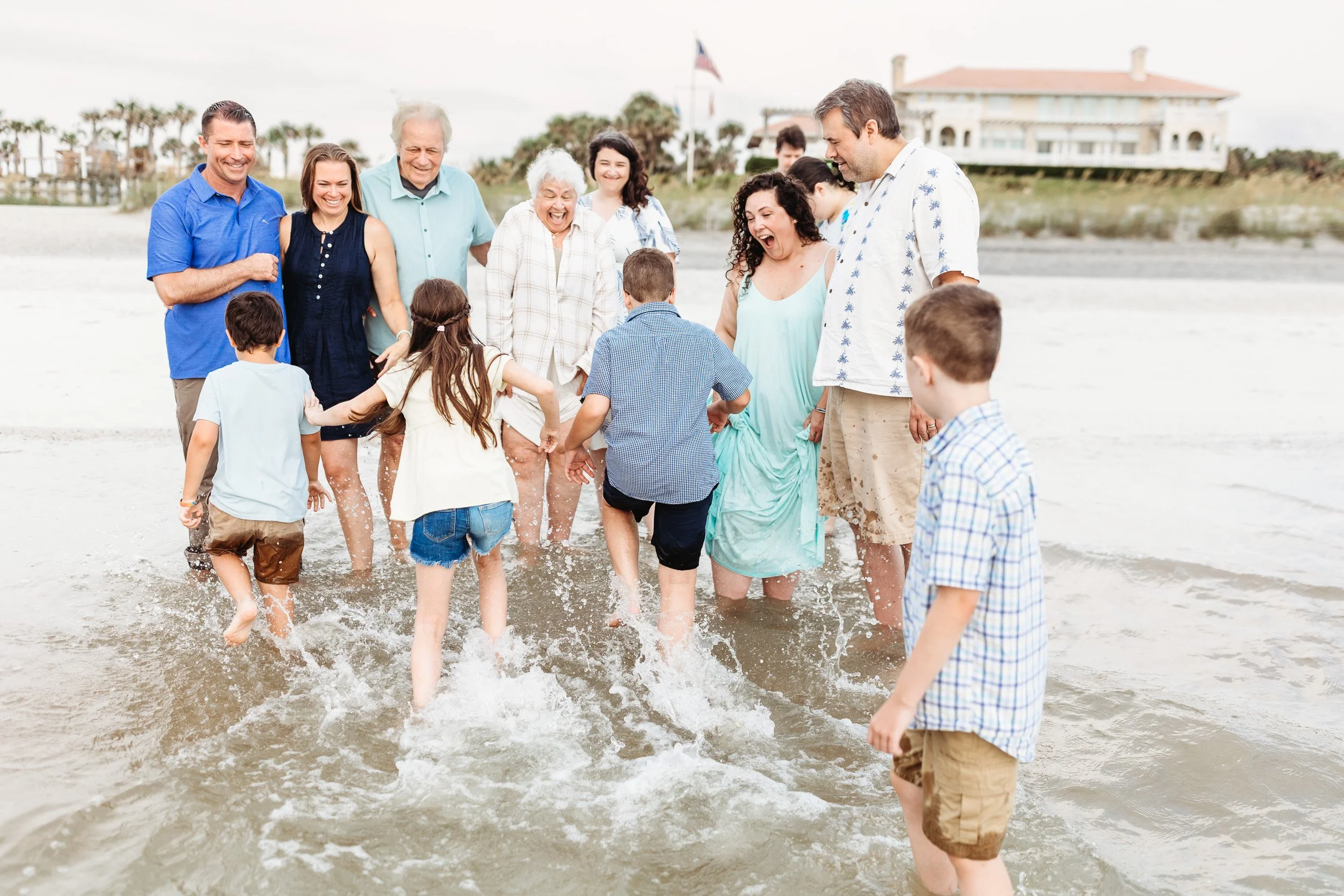 kids in the ocean running towards grandparents splashing water on them and everyone is laughing