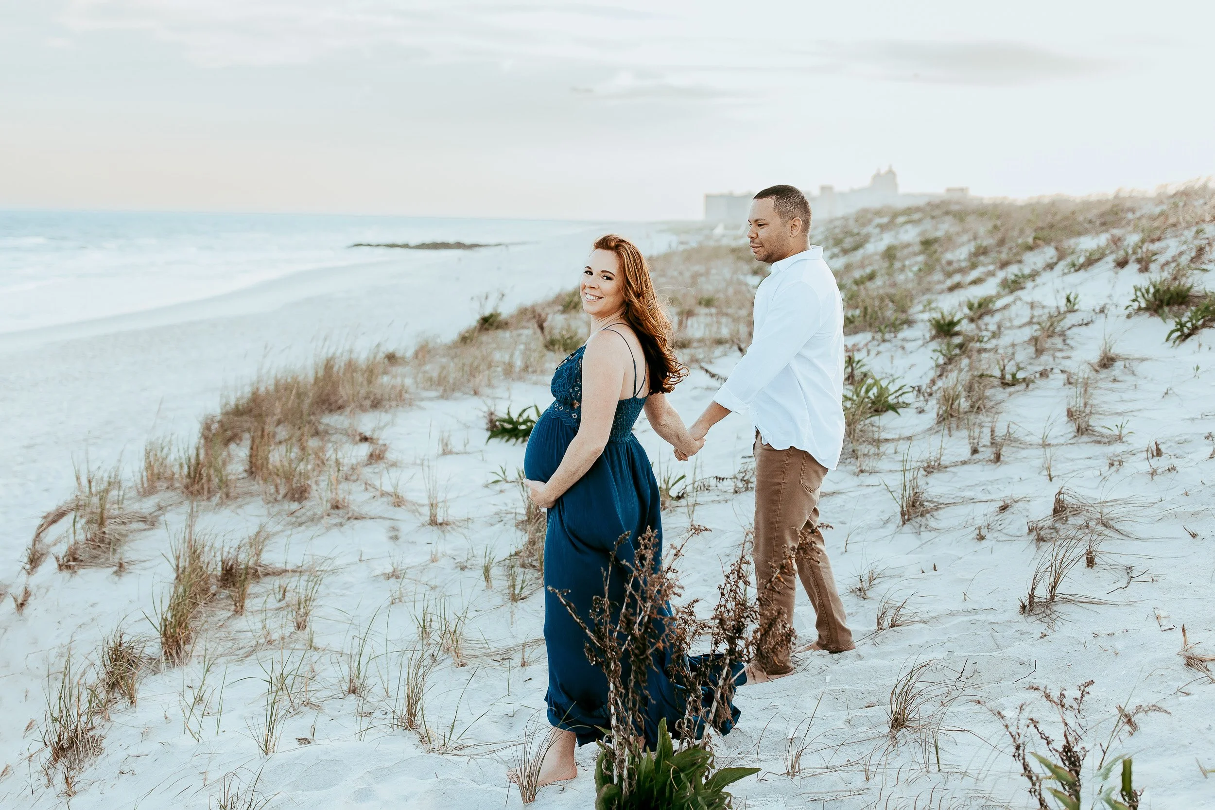 couple holding hands while walking down a dune in Jacksonville Beach