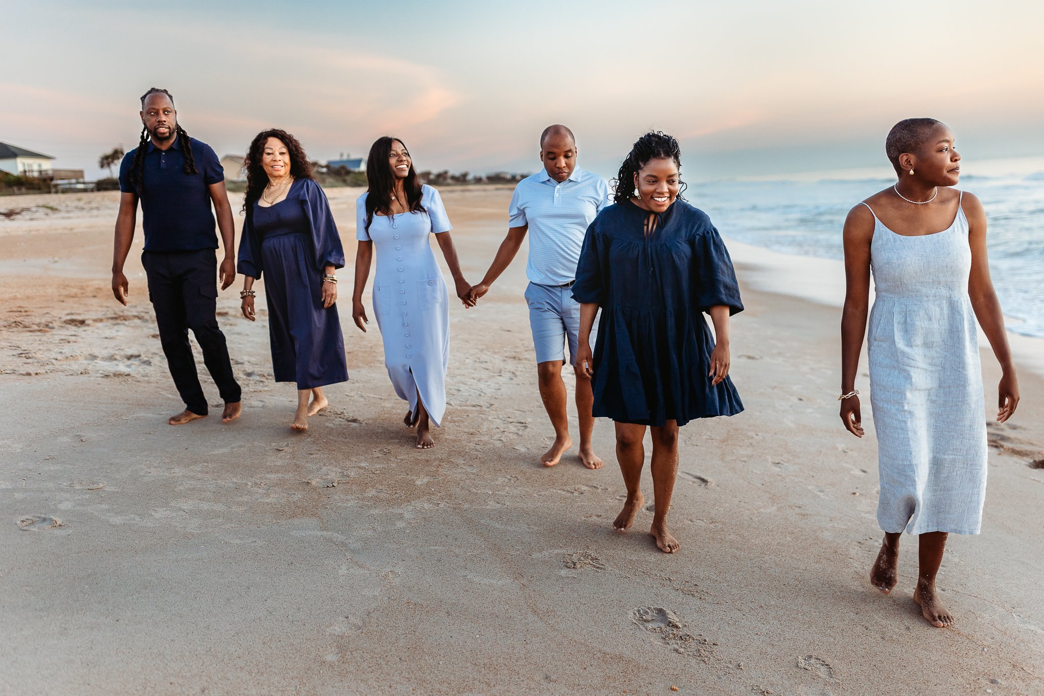 family walking together along the shoreline in the early morning with soft natural light