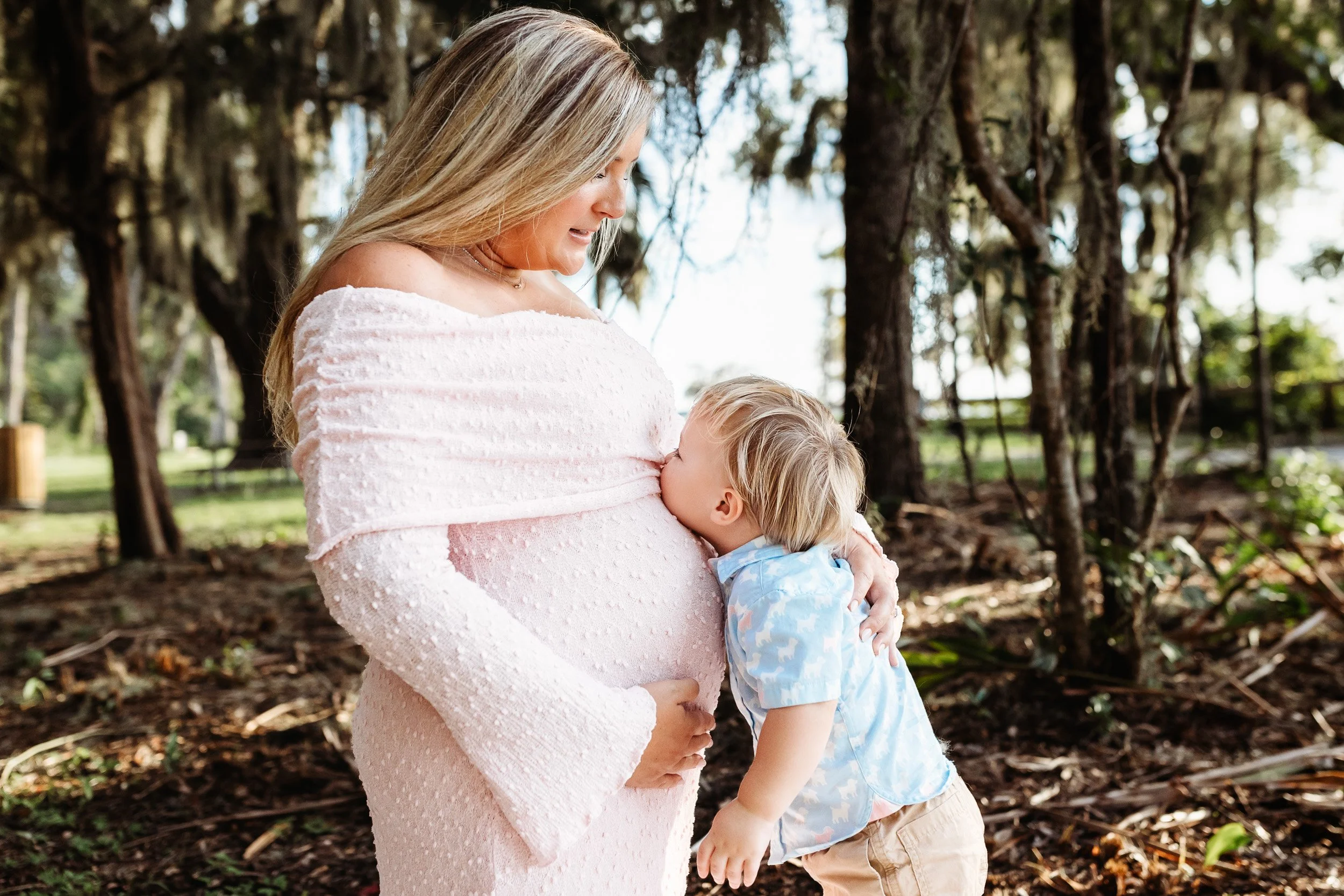 Toddler gently touching their mother's baby bump during a maternity session.