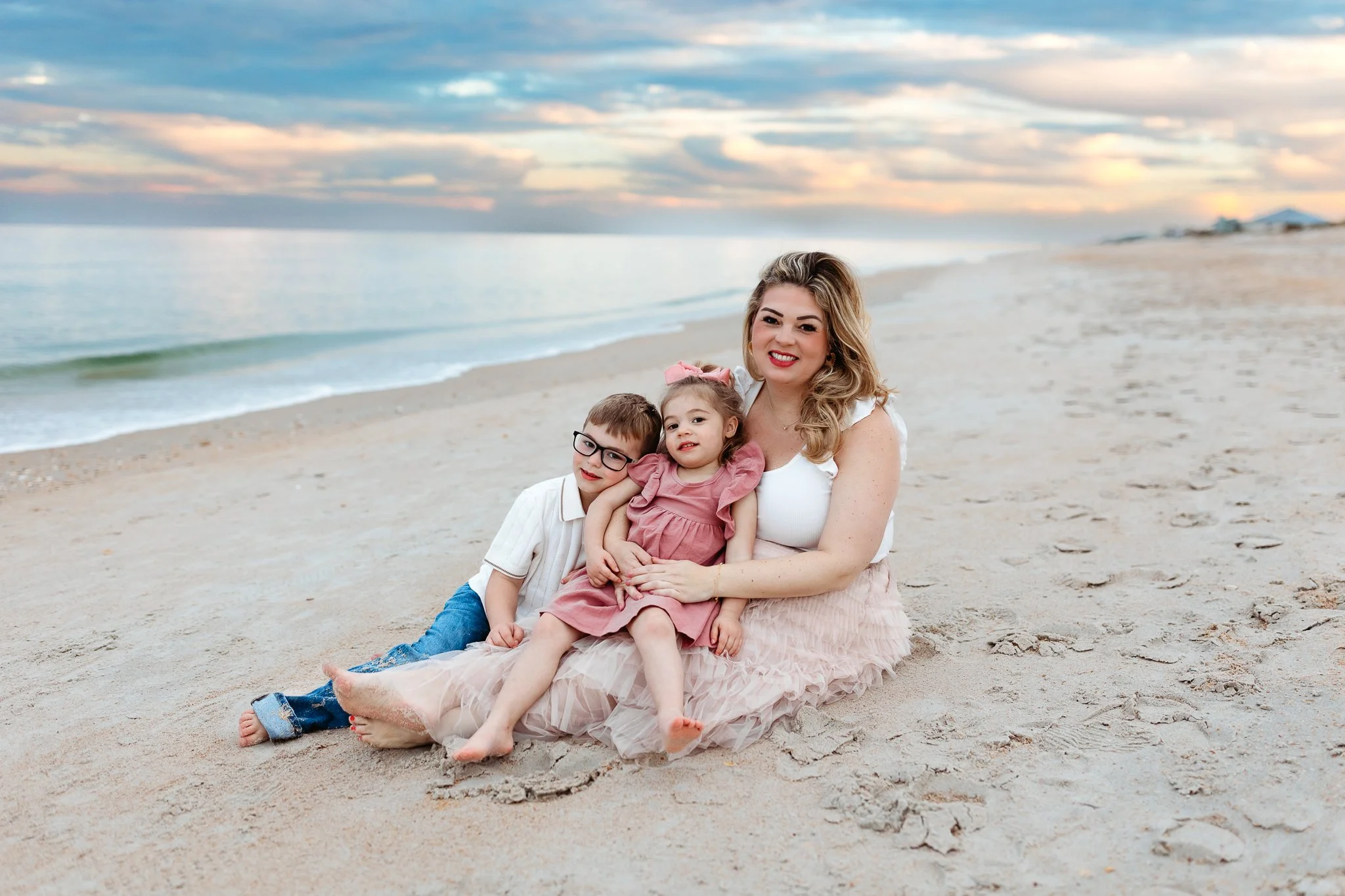 mother embracing children on the beach at sunset